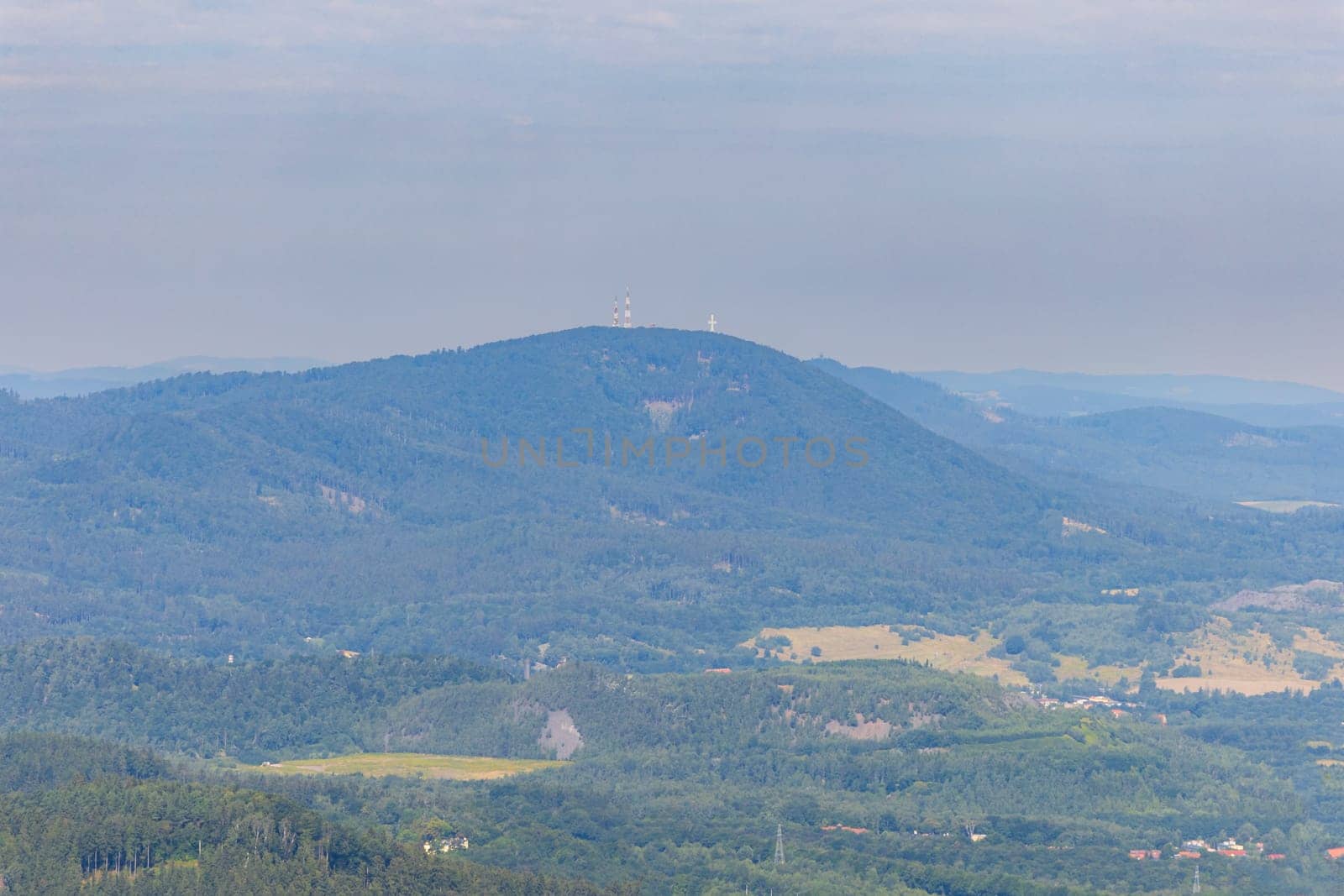 Beautiful green and blue panorama of layers of mountains and trees and some fields seen from top of viewing tower at highest mountain in this area by Wierzchu