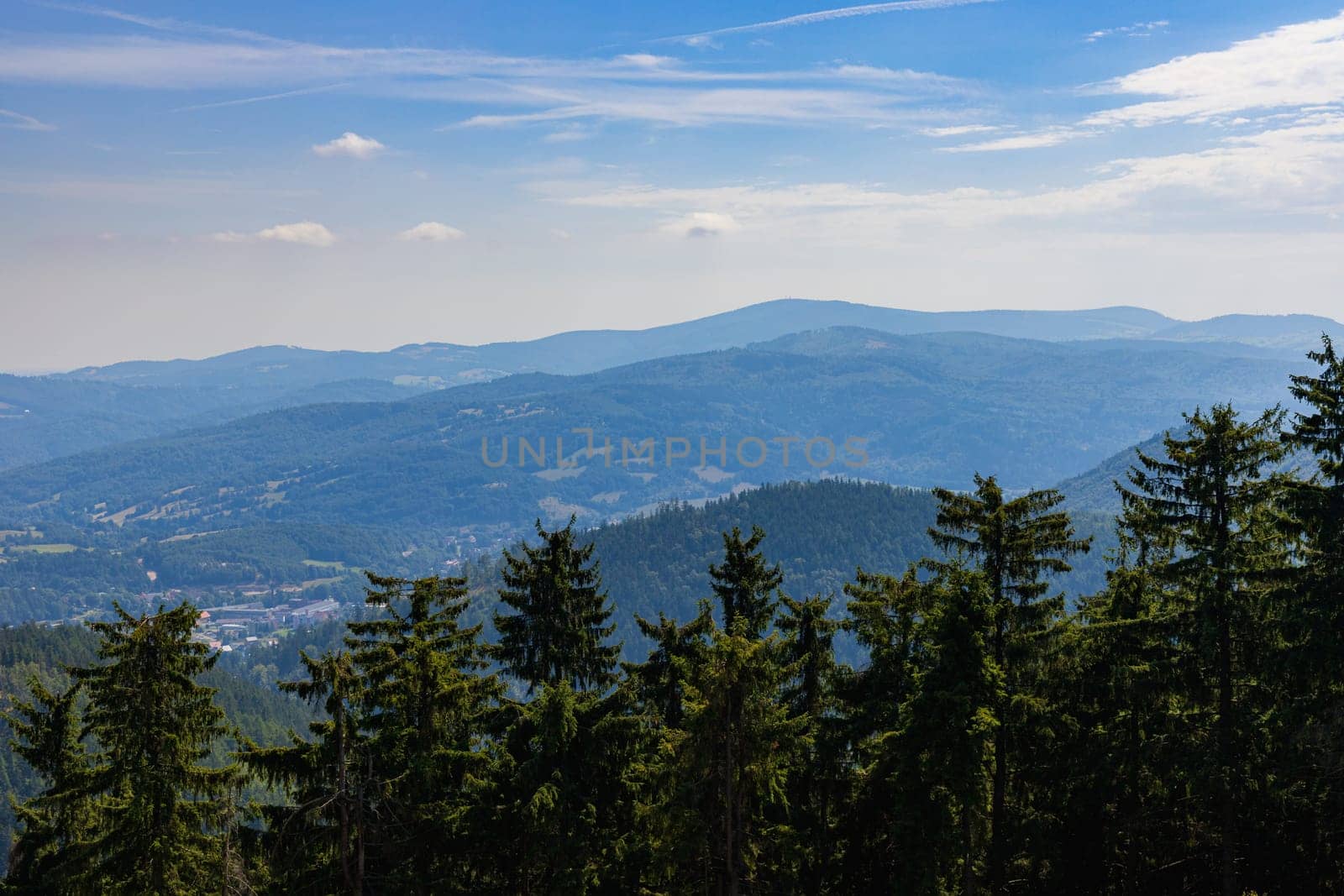 Beautiful green and blue panorama of layers of mountains and trees and some fields seen from top of viewing tower at highest mountain in this area by Wierzchu