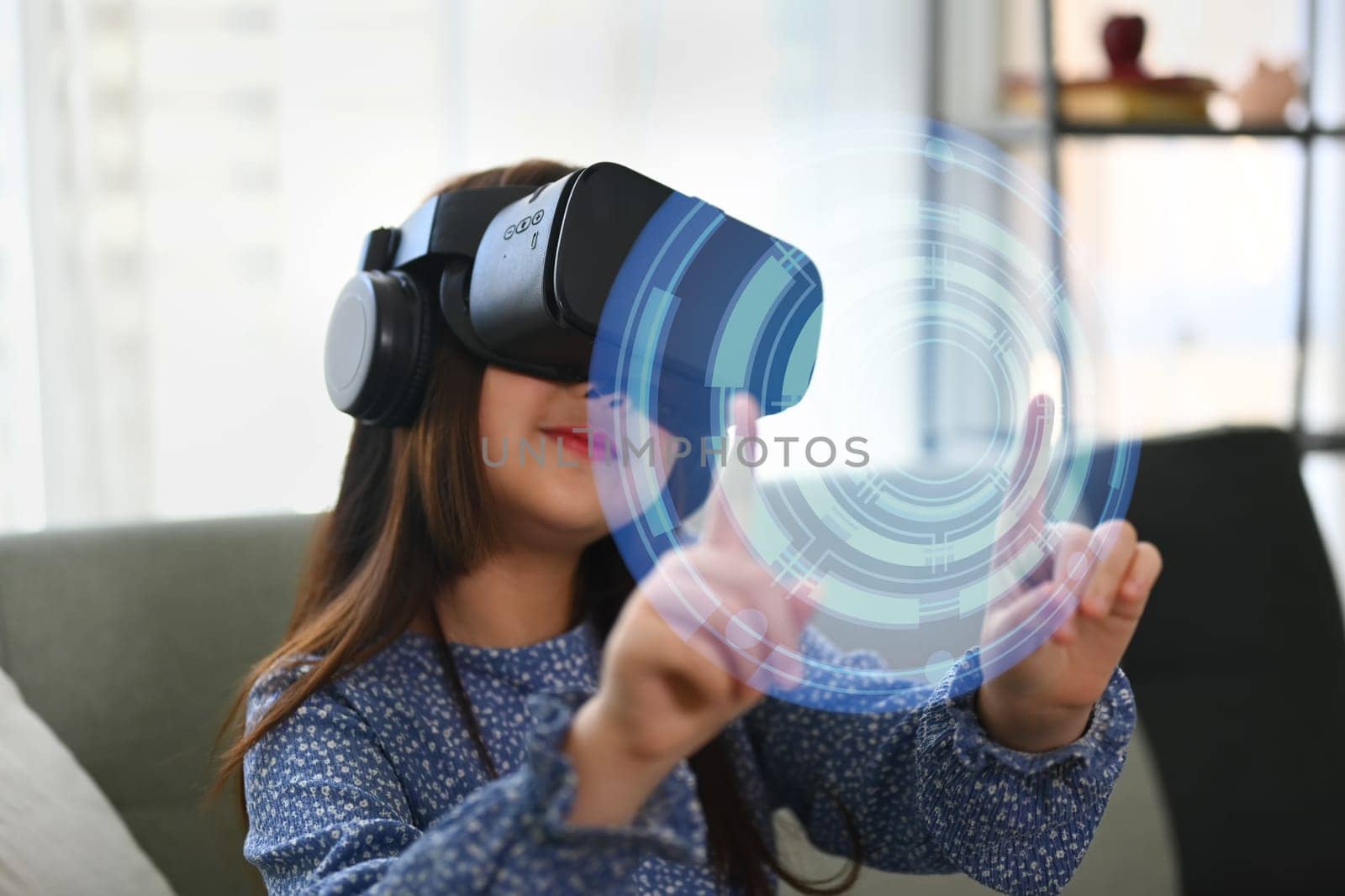 Happy child girl in VR headset touching virtual screen. Concept of futuristic technology. by prathanchorruangsak