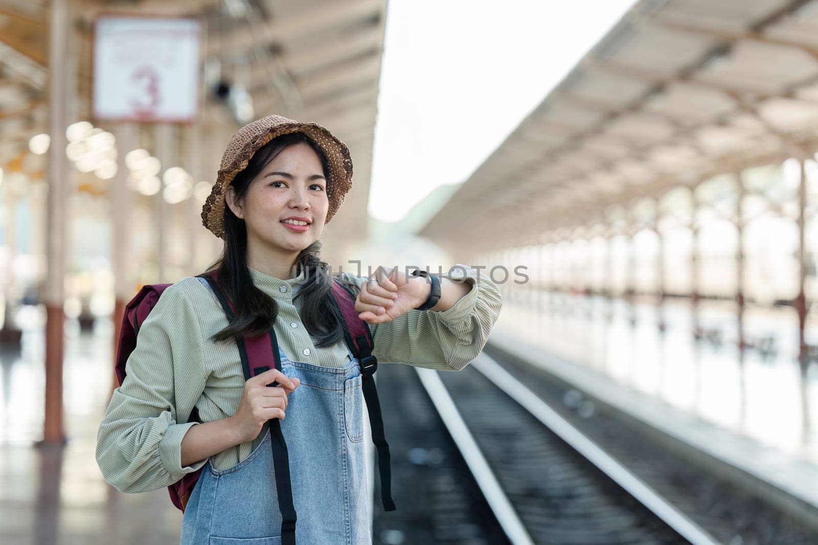 Young woman looking at smart watch with backpack. Young woman waiting for train.