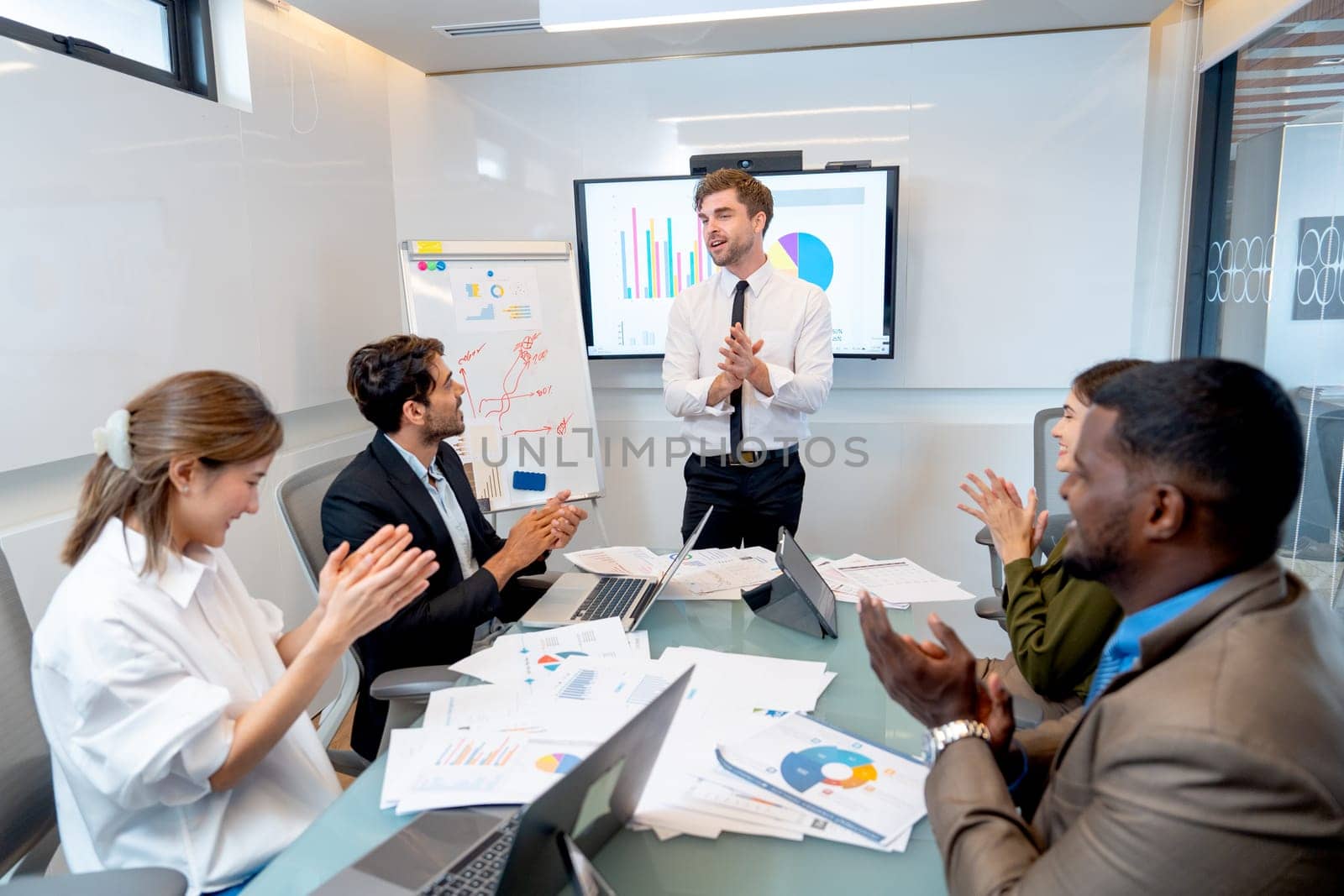 Caucasian manager stand in front of meeting room to express happiness about the success of their project with clapping their hands to celebrate together.