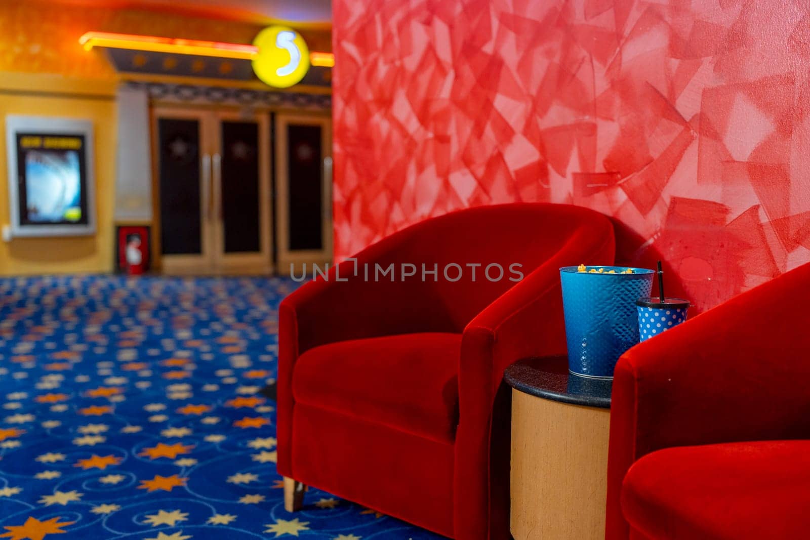 The area of in front gate of the movie theater with red chair and also popcorn and drink on table. Concept of happy time for entertainment to relax on holiday.