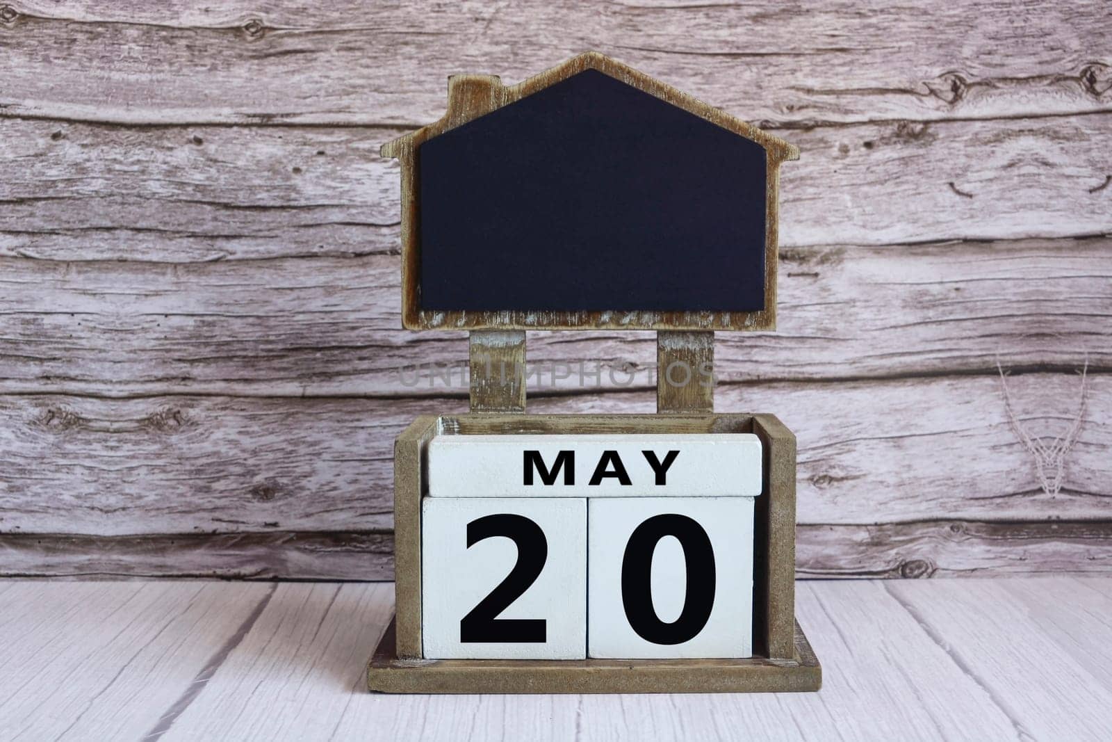 Chalkboard with May 20 calendar date on white cube block on wooden table.