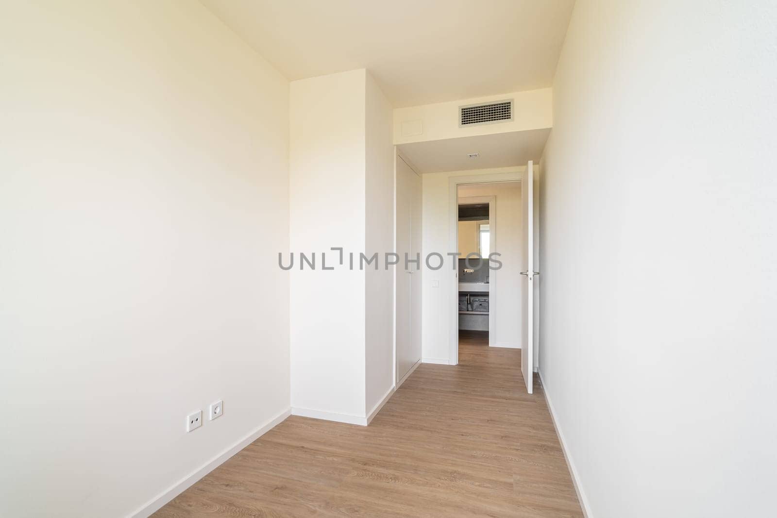 Empty rectangular premise for kitchen after renovation. Narrow unfurnished room with extractor hood over interior door. Unoccupied apartment
