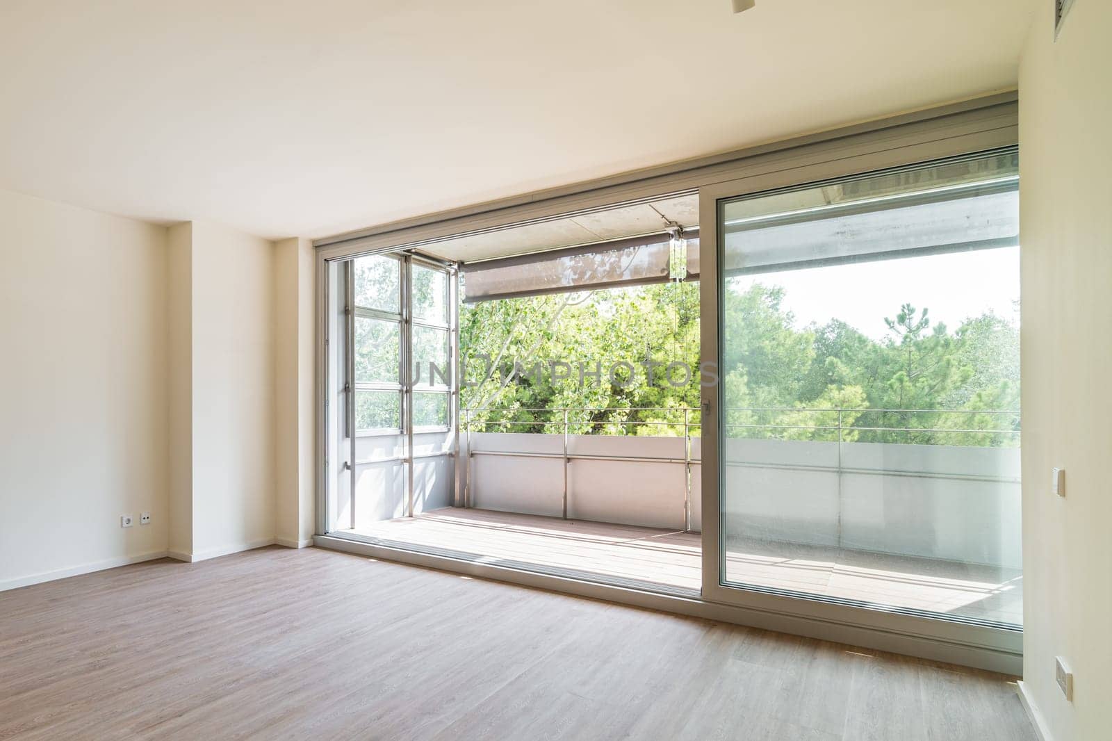 Panoramic large window to balcony from empty bedroom. Spacious place for sleep with nature view after designer renovation without furniture