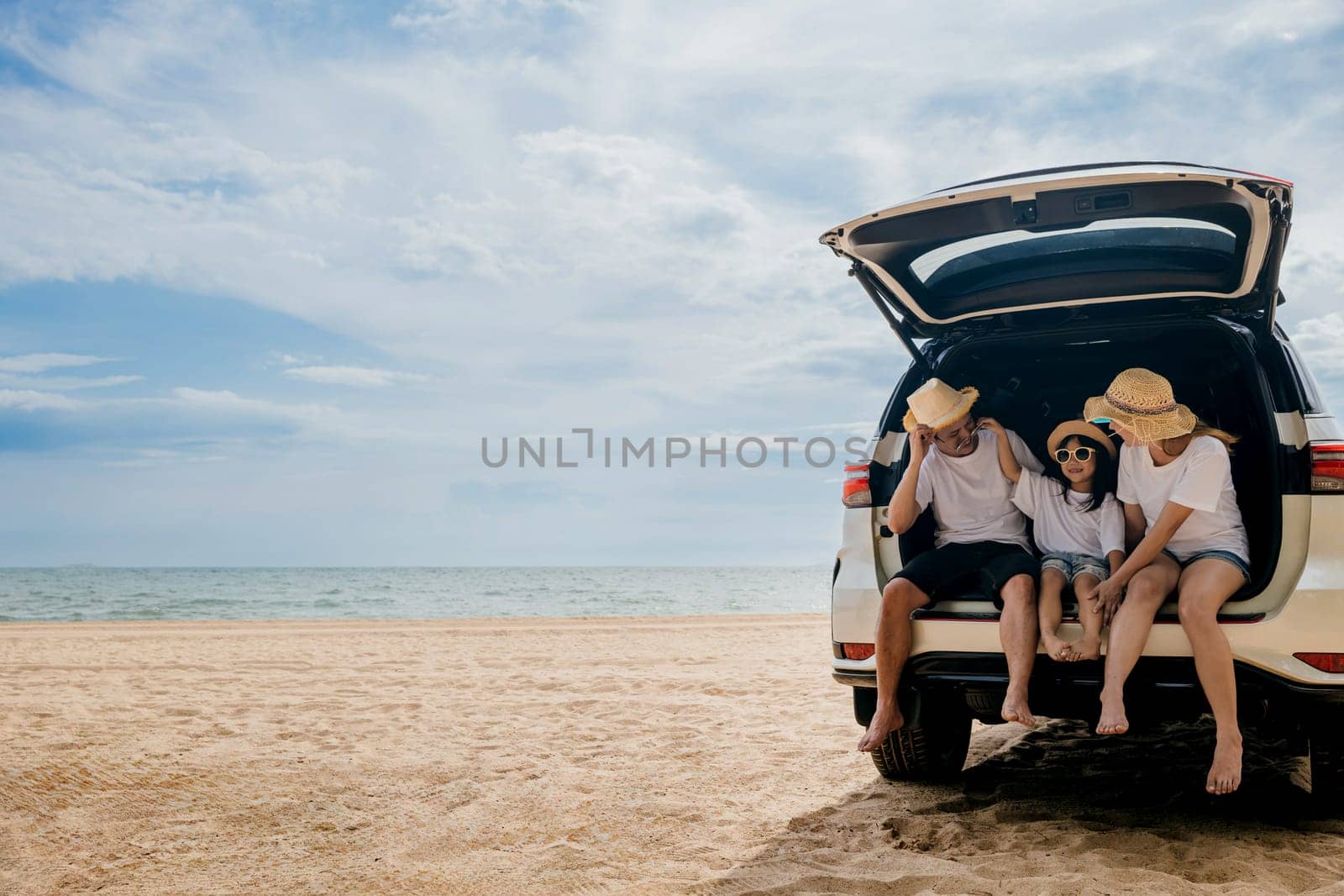 People enjoying road trip sitting down on back their car by Sorapop