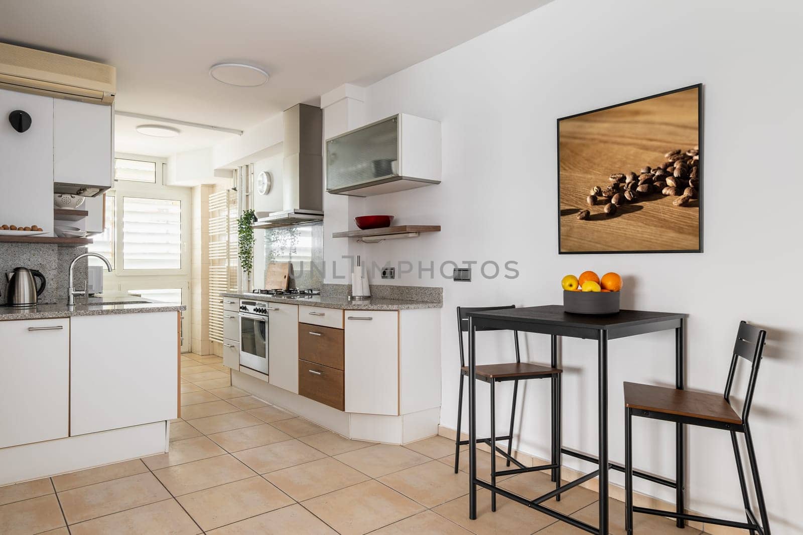 Kitchen area with units and high table to eat in smart apartment studio. Light comfortable room for cooking and rest in renovated residential house