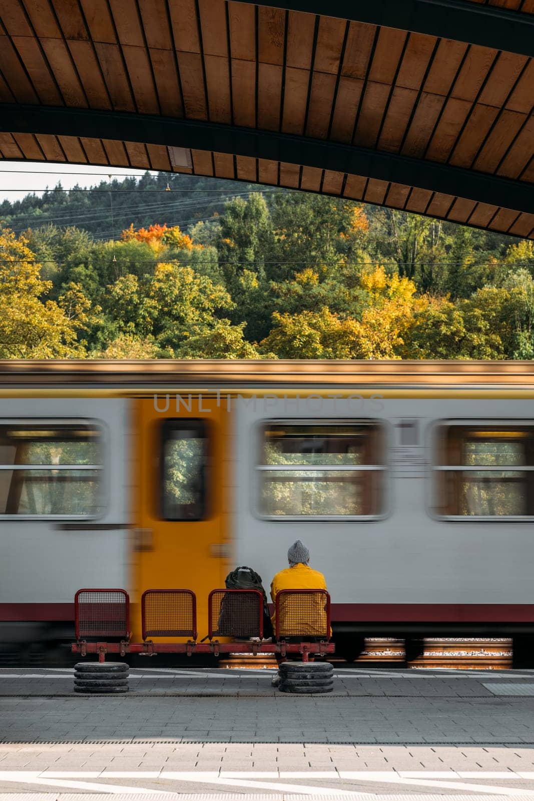 Train arrives at station where passenger sits waiting for journey by apavlin