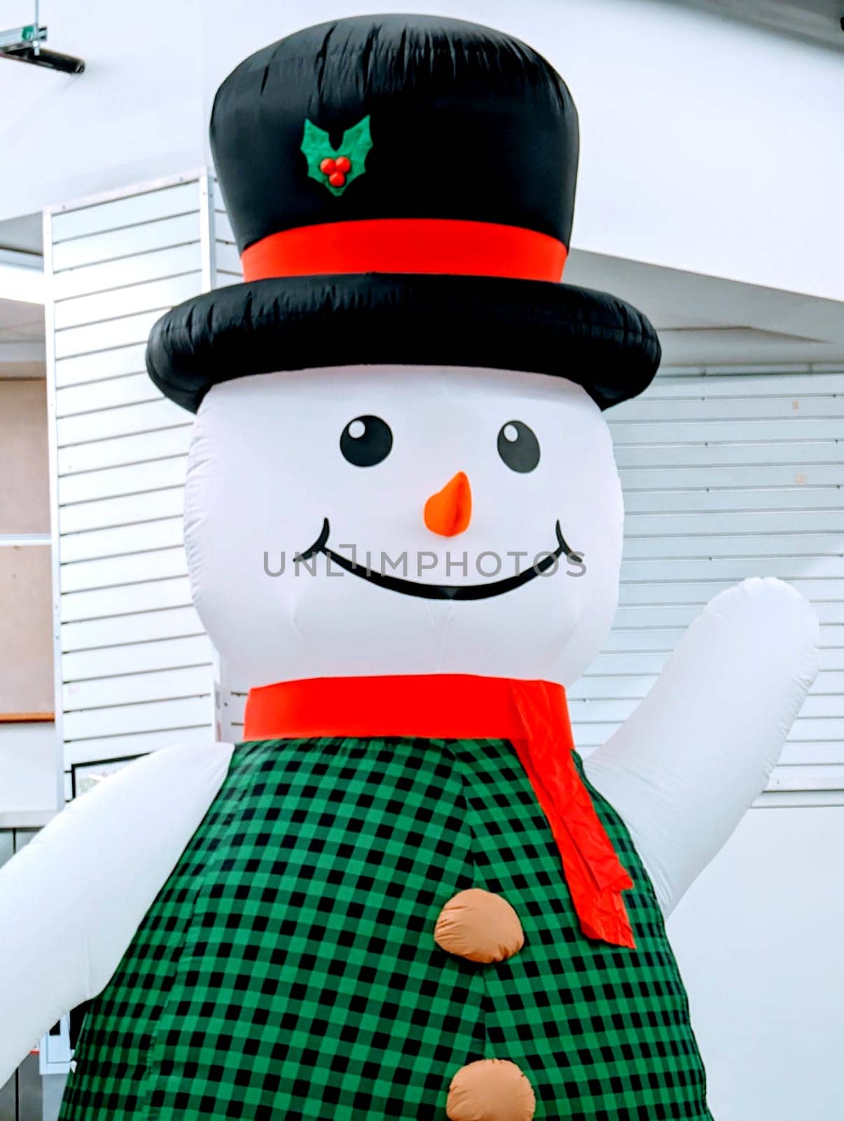 Honolulu - December 5, 2023: Festive inflatable snowman decoration with a black top hat and a green and black plaid scarf. The snowman has an orange carrot nose and black coal eyes and mouth. 