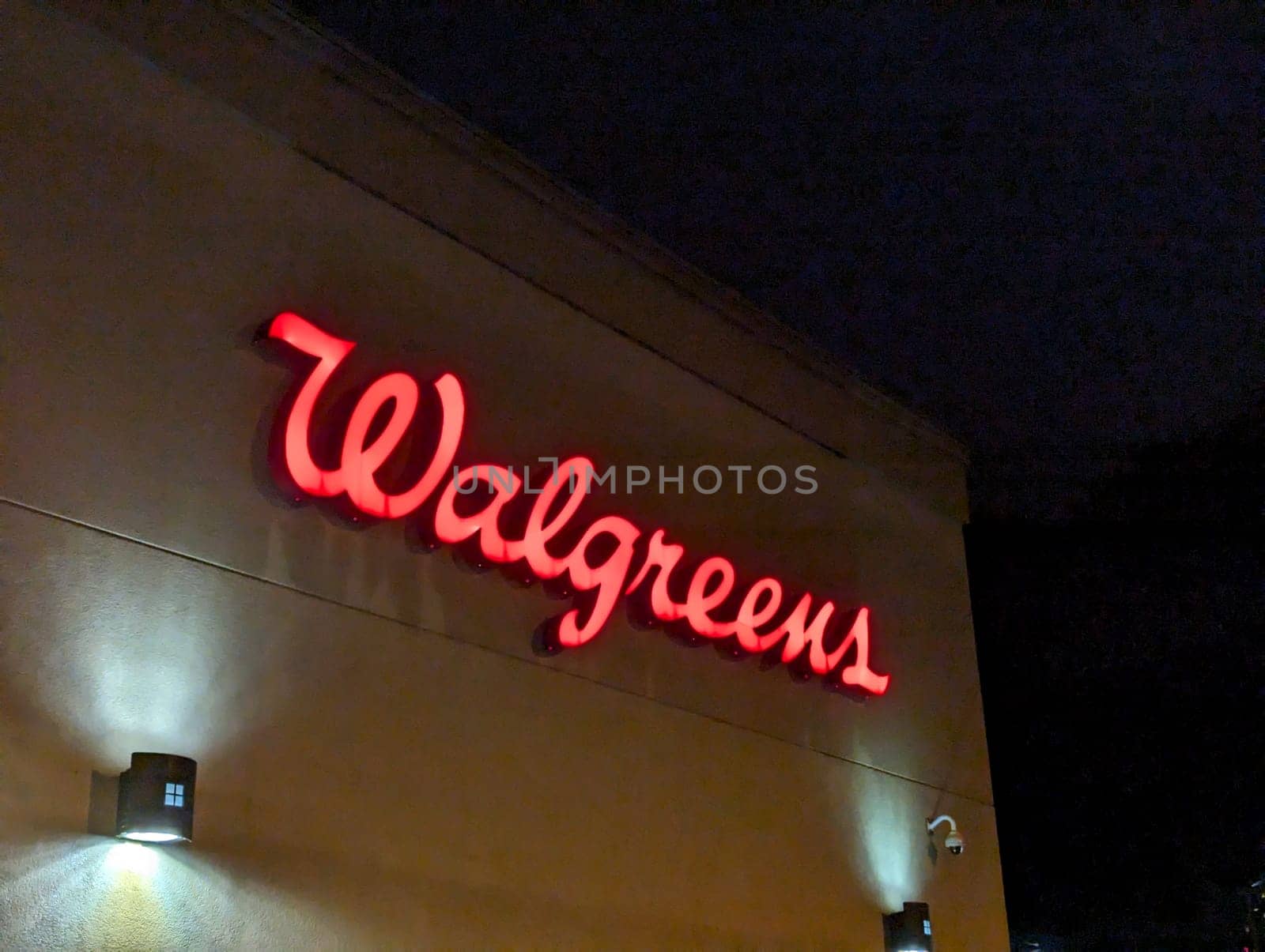 Honolulu - August 25, 2023:  Walgreens logo, a red cursive writing, on a beige building at night. The logo is lit up and stands out against the dark sky. 