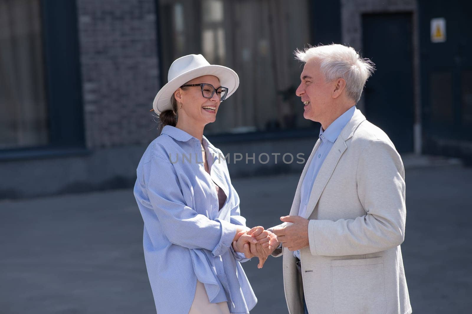 Stylish elderly laughing couple on a walk. Romantic relationships of mature people