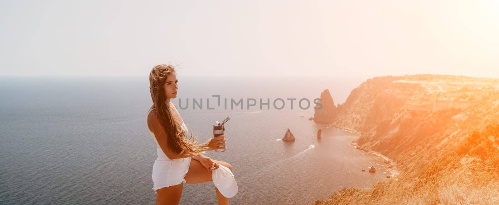 Woman summer travel sea. Happy tourist enjoy taking picture outdoors for memories. Woman traveler posing over sea bay surrounded by volcanic mountains, sharing travel adventure journey by panophotograph