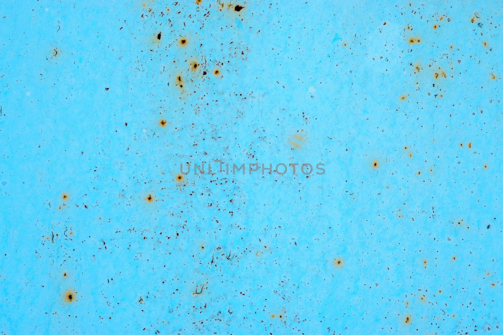 Blue metal surface with spots creating textured wall background