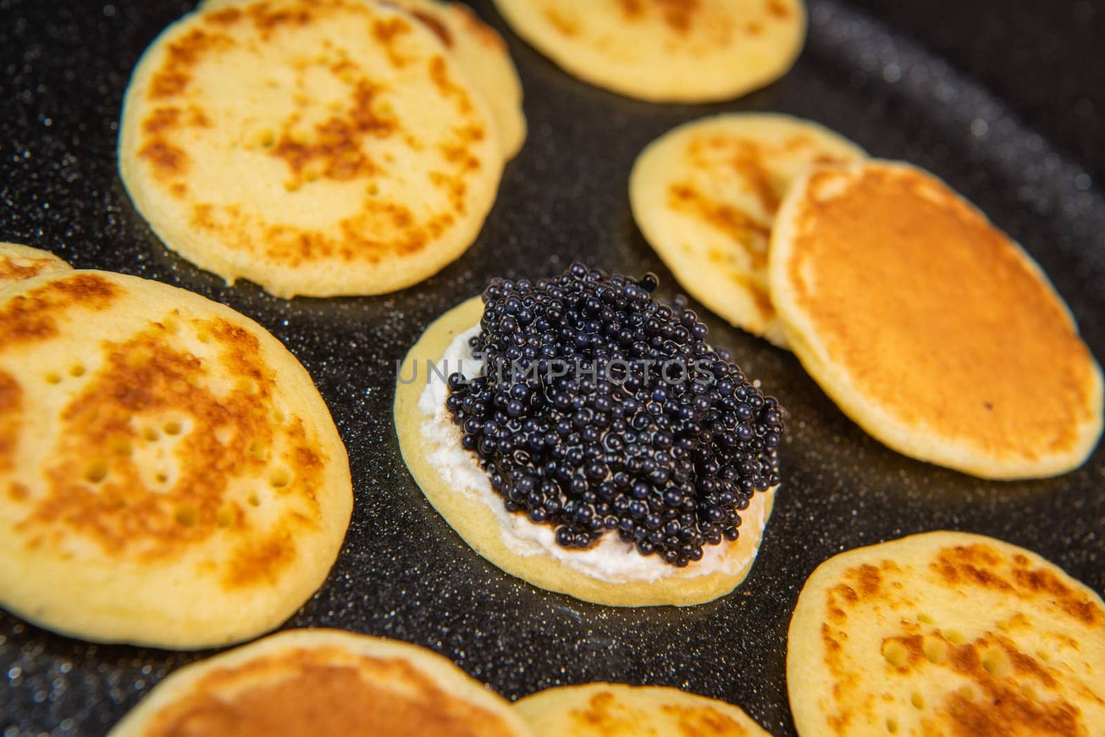 Blinis with black caviar and cream cheese, on a festive dish, mini pancakes, an elegant appetizer, High quality photo