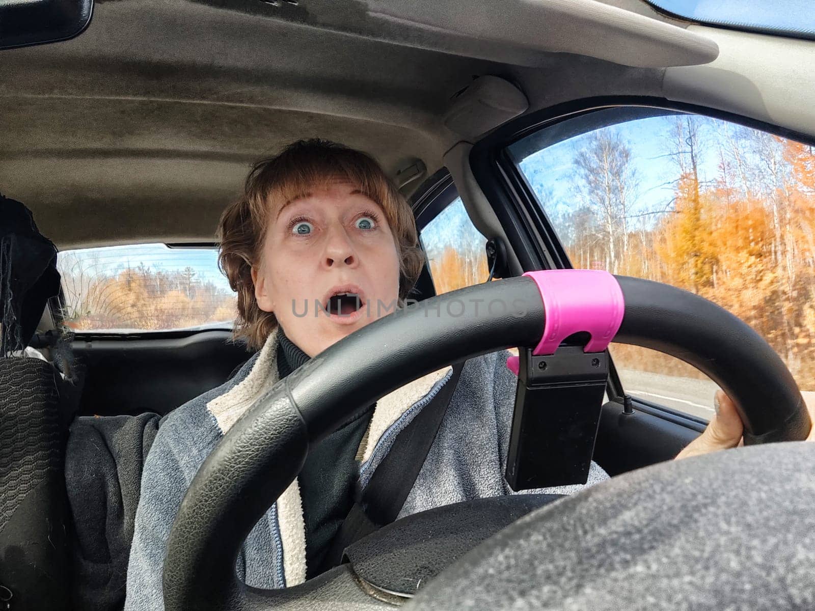 Terrified female driver a second before the accident. Scared middle-aged adult woman holds the steering wheel of a car. Frightened Lady girl who is owner or rent a car for travel by keleny