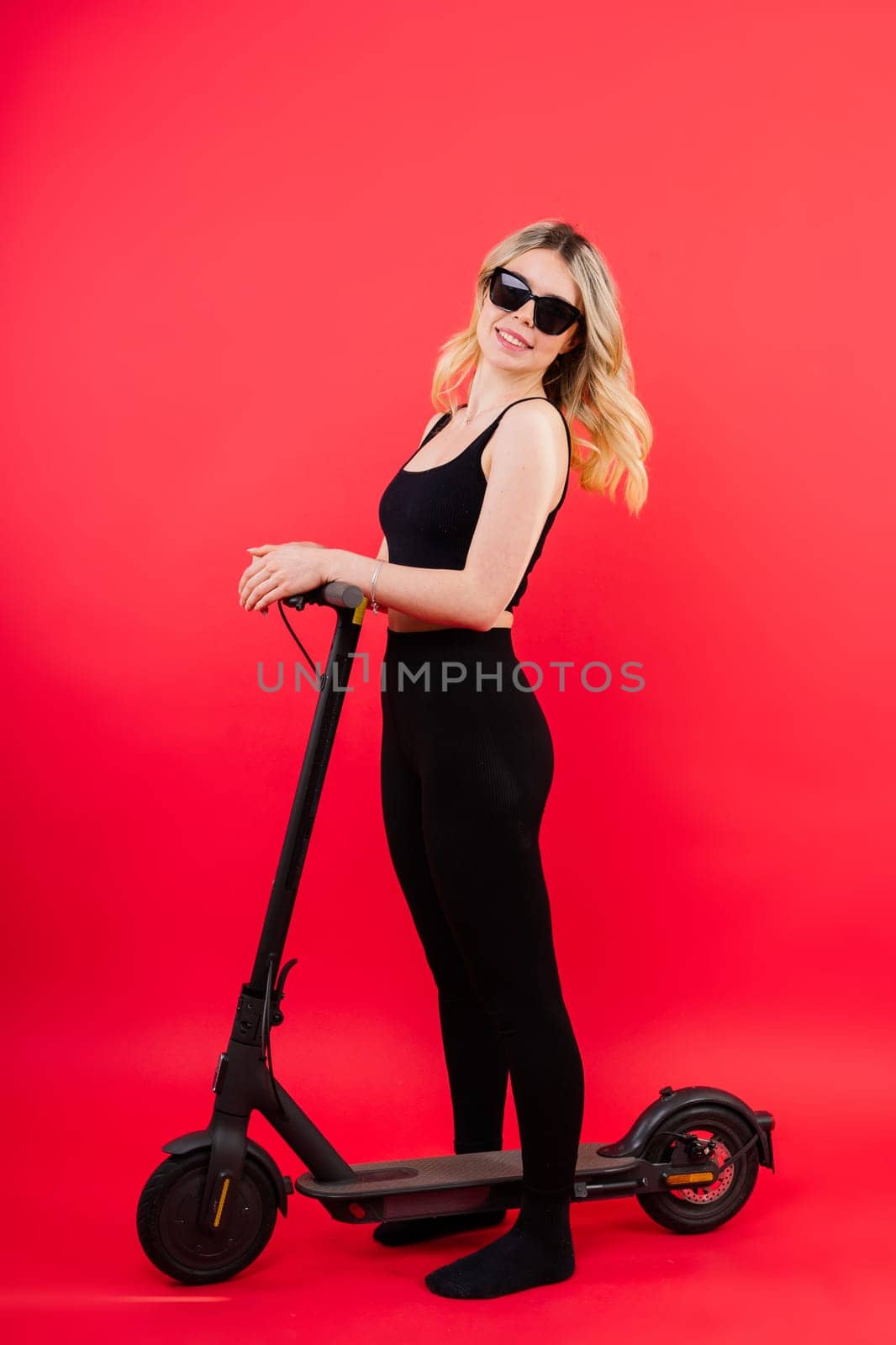 Happy young woman wear glasses riding electric scooter on background studio People lifestyle concept by Zelenin