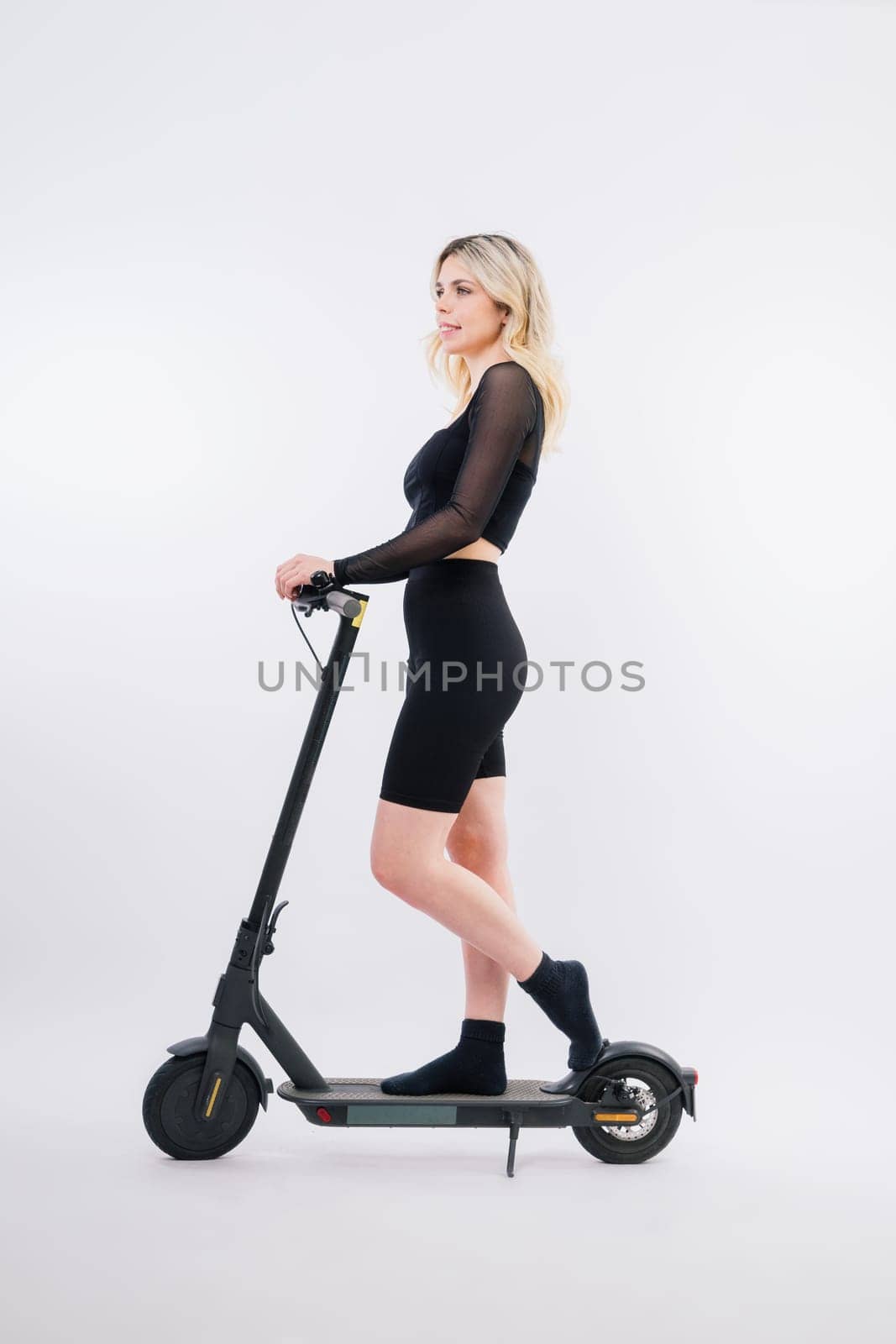 Happy young woman wear glasses riding electric scooter on background studio People lifestyle concept by Zelenin