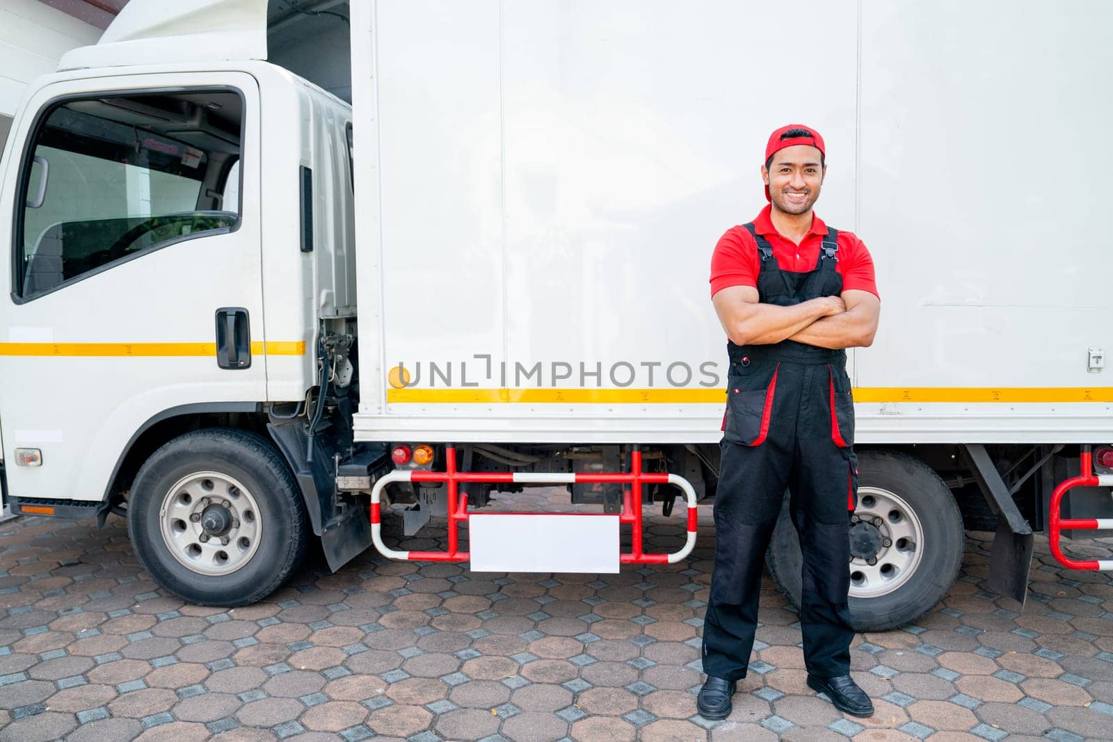 Portrait of Asian delivery man stand beside of truck and arm-crossed also look at camera with smiling after finish to send the product to customer house. by nrradmin