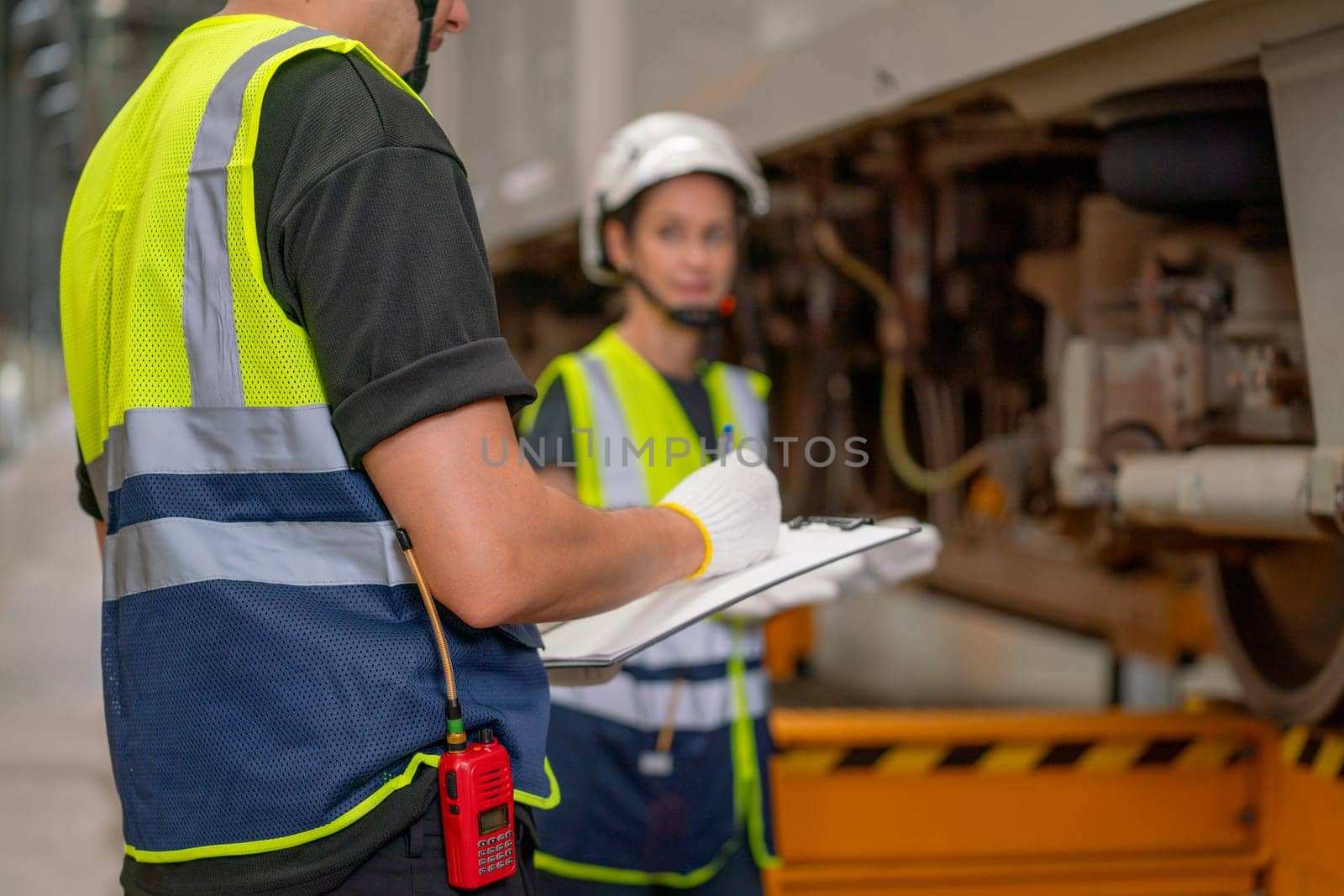 Close up hands of technician or engineer worker record the data about the checking and maintenance list and work with his co-worker woman in workplace.