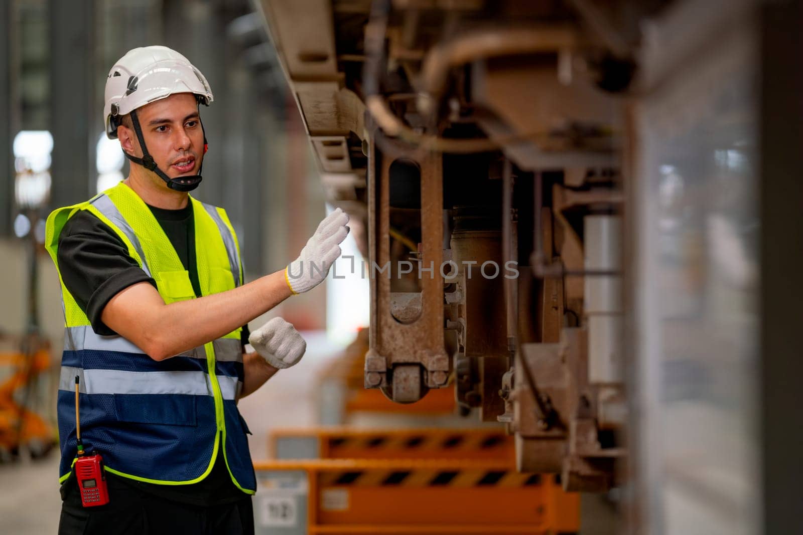 Professional engineer or technician man check and maintenance lower parts of electric train in workplace area.