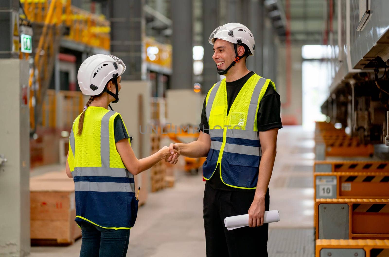 Engineer or factory technician worker man and woman shake hands for the success of joined project together in workplace near the electric train on rail.