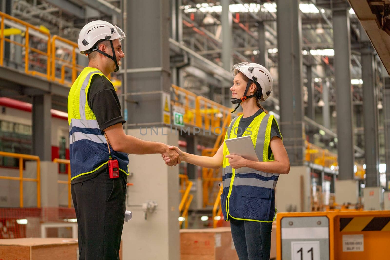 Professional engineer or factory technician worker man and woman shake hands for the success of joined project together in workplace.