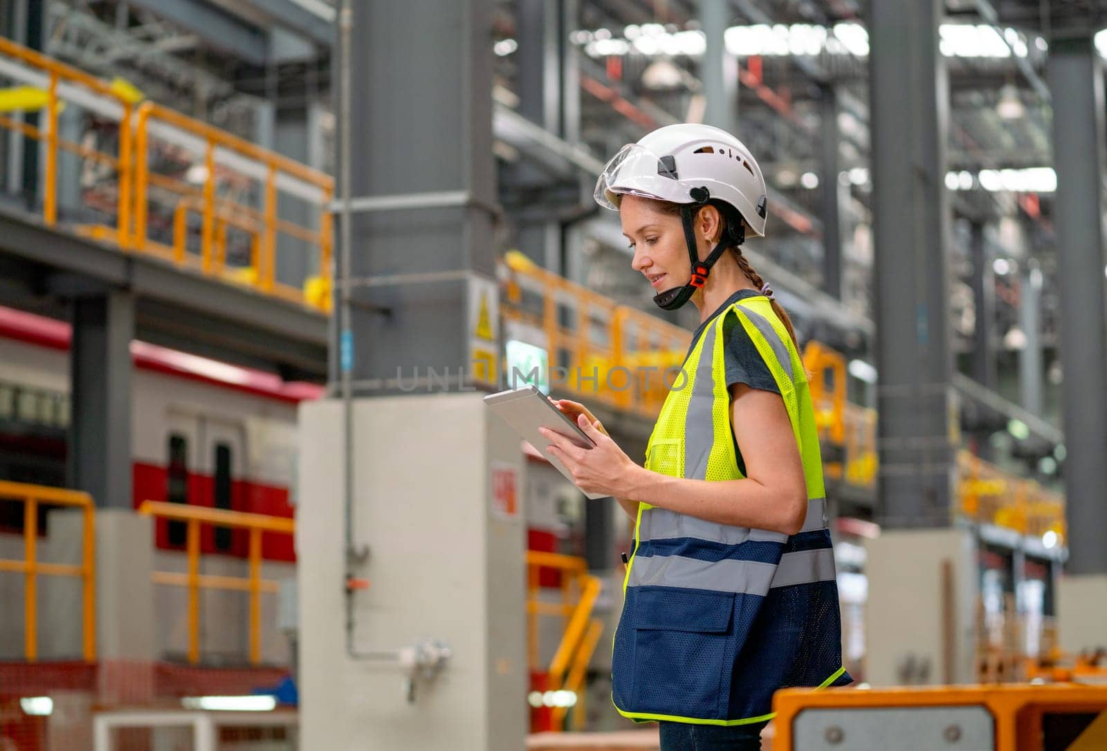 Side view of professional engineer or technician factory worker hold tablet and look to the left and stay in factory workplace area. by nrradmin