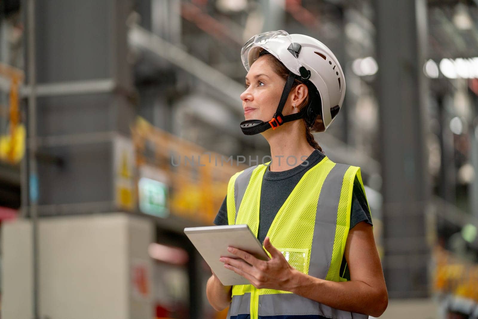 Portrait of professional engineer or technician factory worker hold tablet and look to the left and stay in factory workplace area.