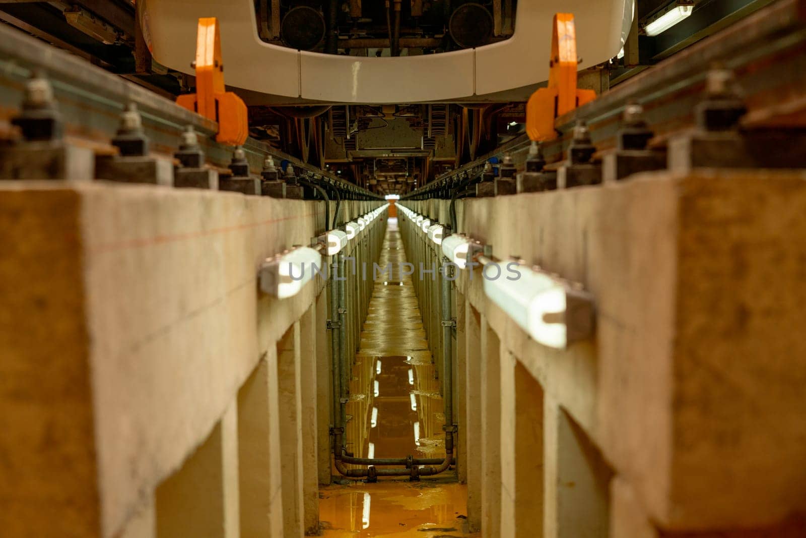 The area under rail of electric train in maintenance center that contain light along the rail that may help support for technician and worker to work.