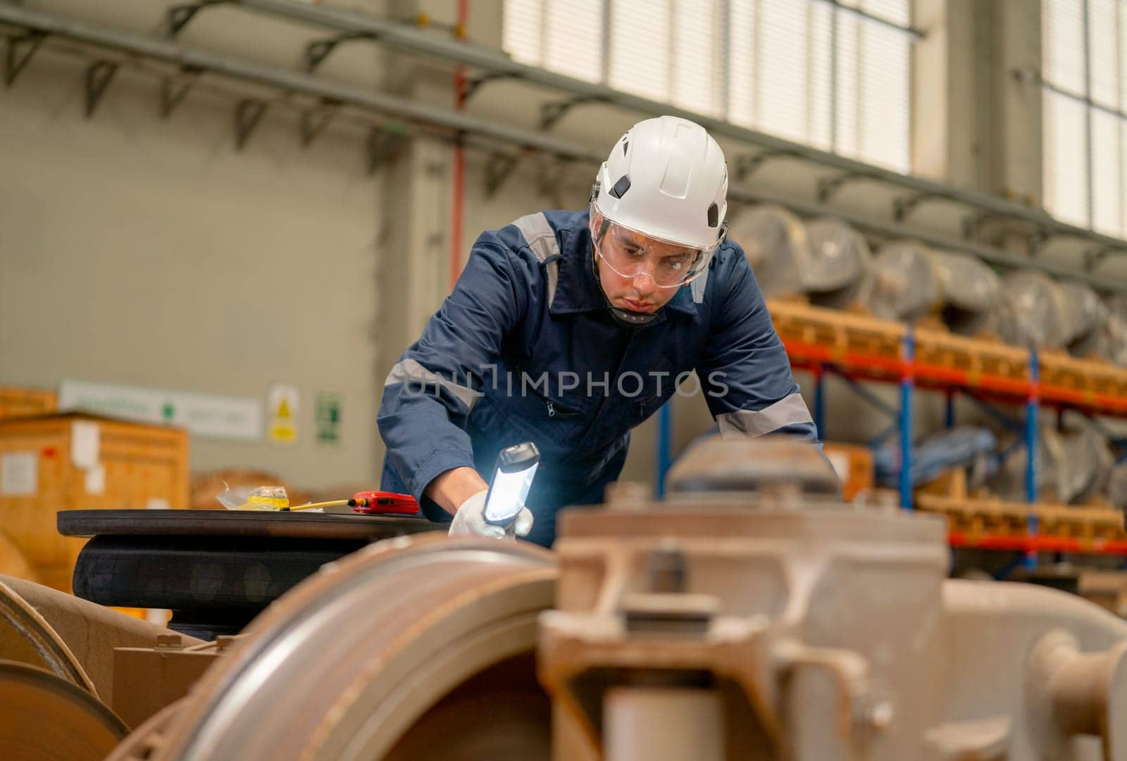 Professional technician or engineer worker hold light stick to check and fix the problem of part of electric train in factory or maintainence center. by nrradmin