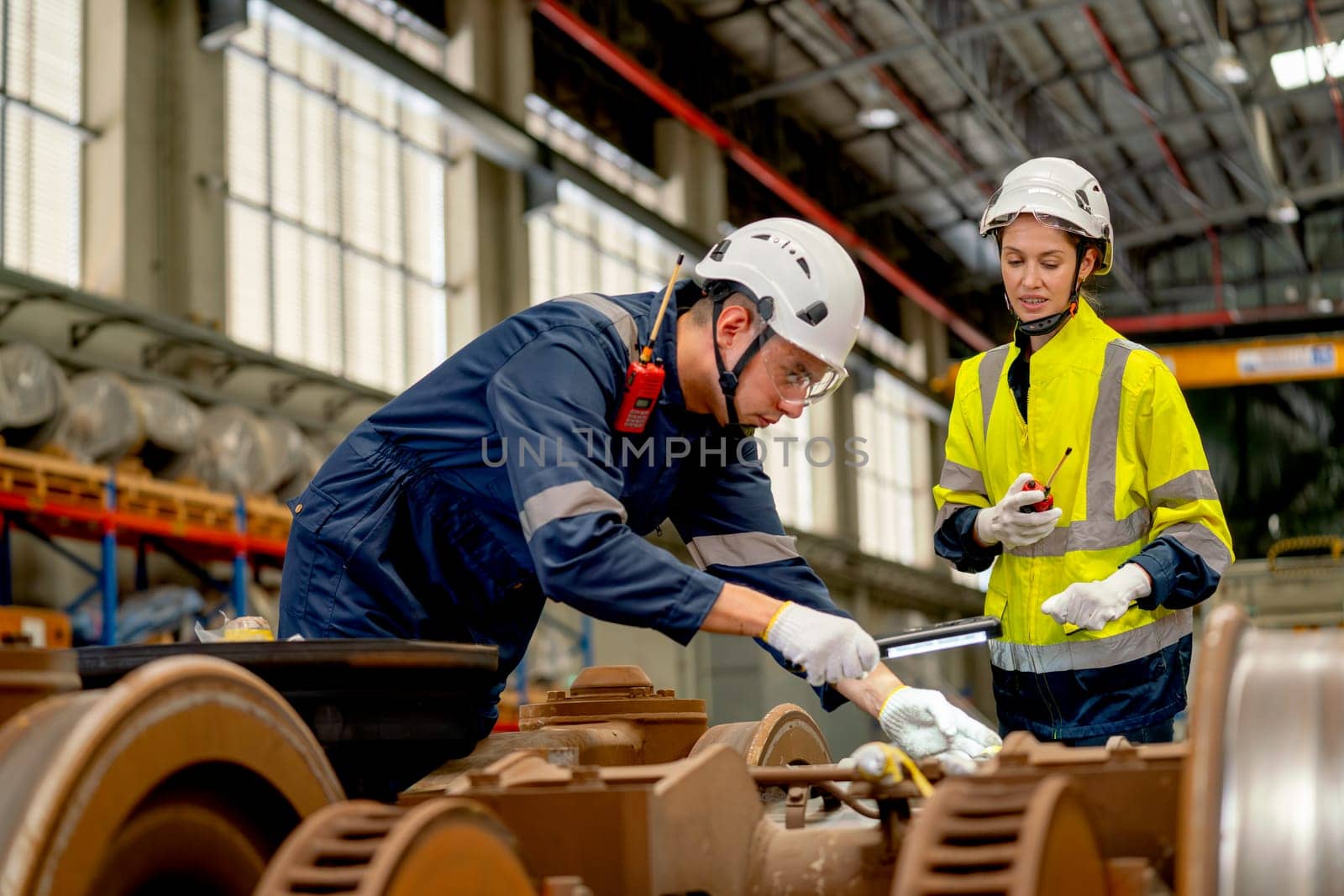 Professional technician or engineer try to check and fix the problem part of electric train and work with factory worker use walkie talkie to contact co-worker team in workplace area.