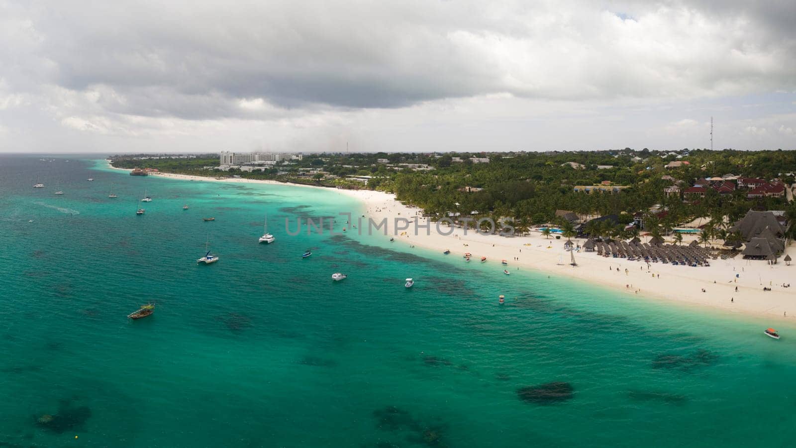 Sandy beach and turquoise ocean in zanzibar at overcast day by Robertobinetti70