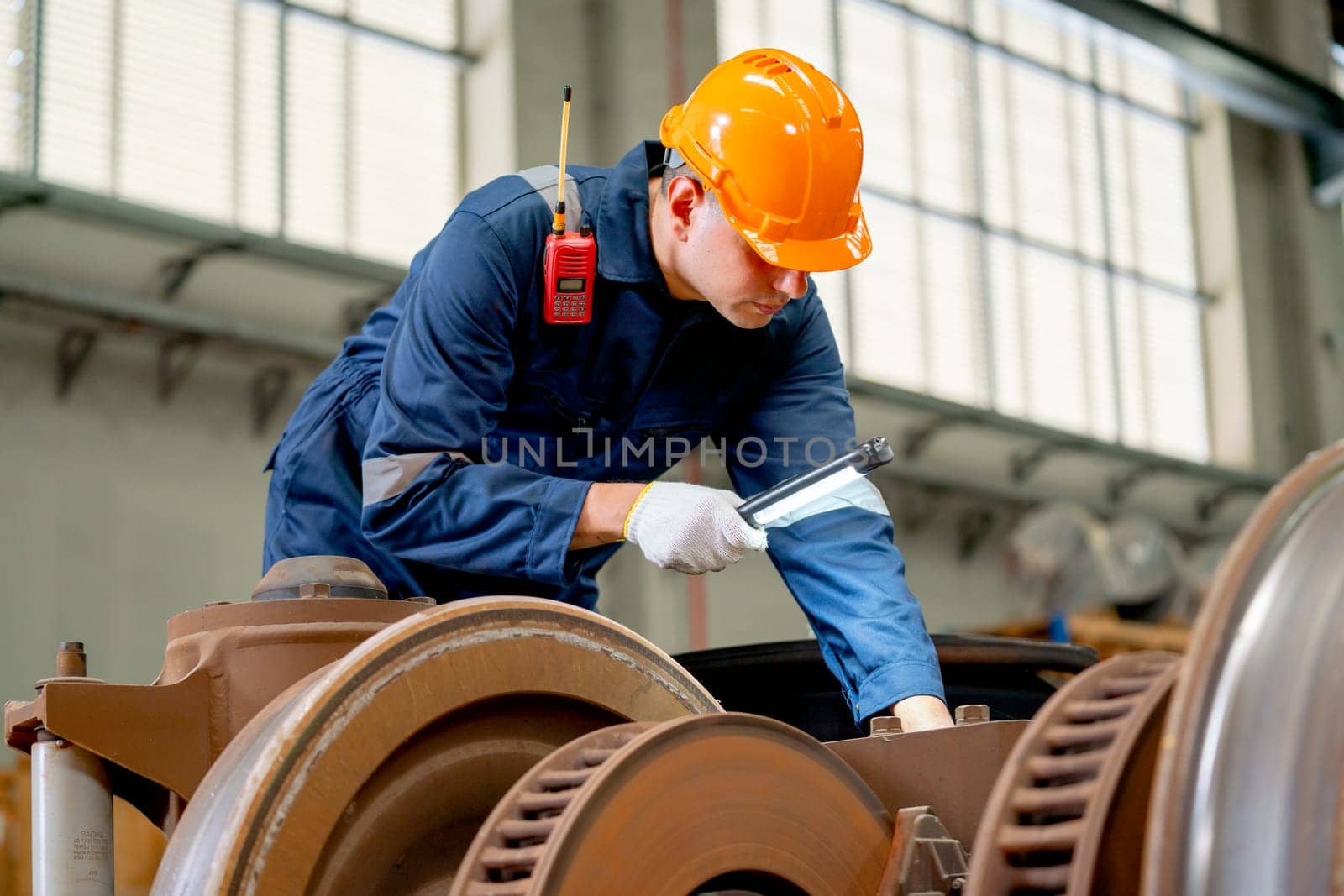 Professional technician or engineer worker hold light stick to check and fix the problem of part of electric train in factory or maintainence center.