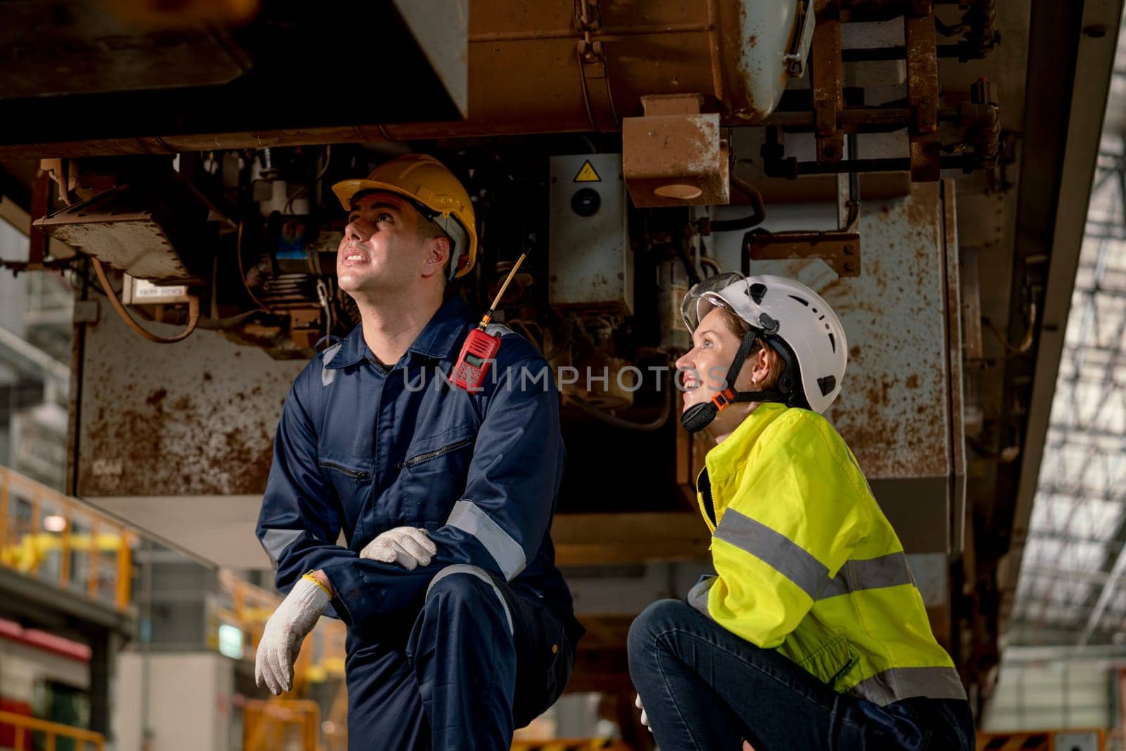 Technician man and train factory worker woman check and fix the problem and stay under electric train in maintenance center.