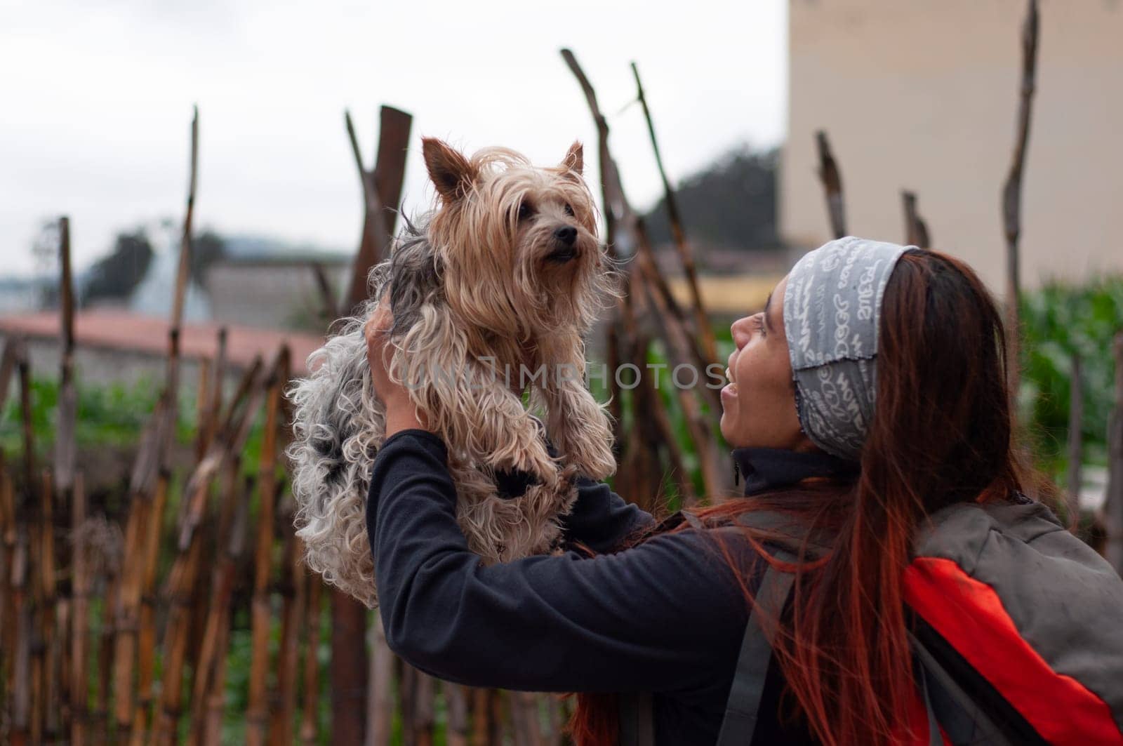 very happy woman holding her dog in her arms making affectionate gestures of love. by Raulmartin