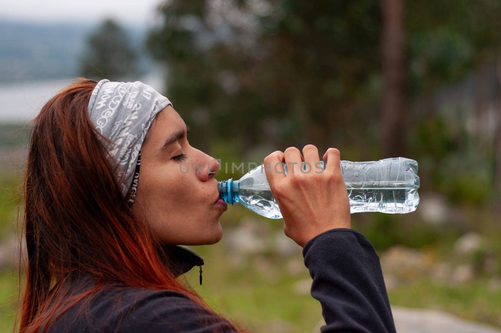 FIRST shot of sporty girl in the mountains drinking a bottle of water. High quality photo