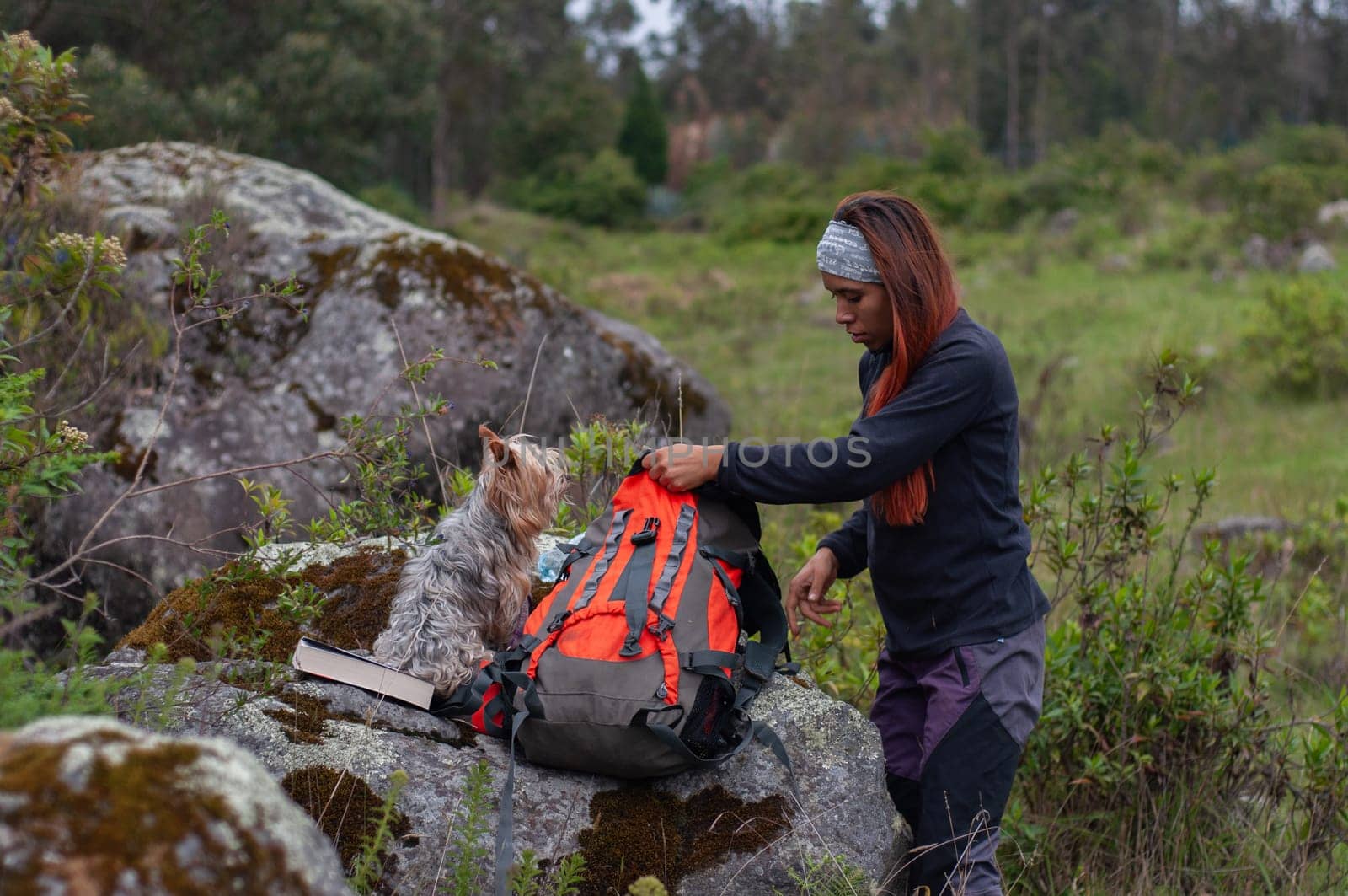 woman preparing her backpack with her dog and her favorite book before going hiking. by Raulmartin