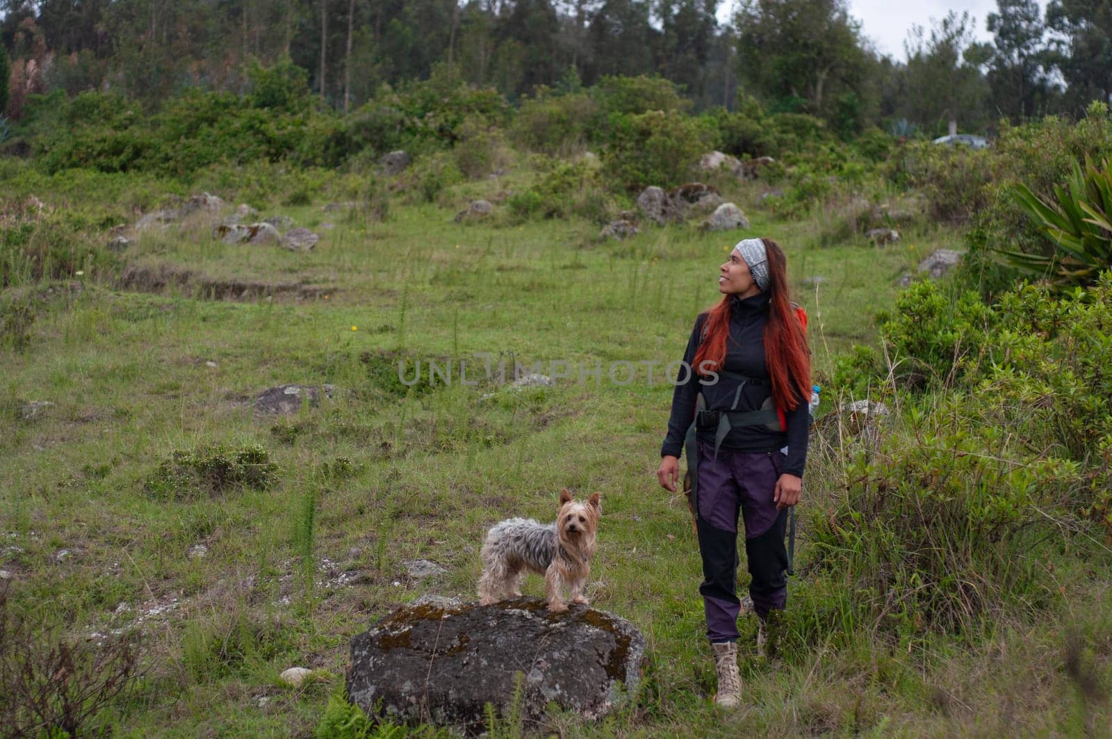 woman explorer admiring the grandeur of the landscape while her dog is on a large rock. High quality photo