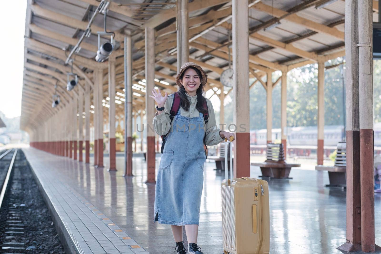 Young Asian woman in modern train station Female backpacker passenger waiting for train at train station to go on holiday. by wichayada