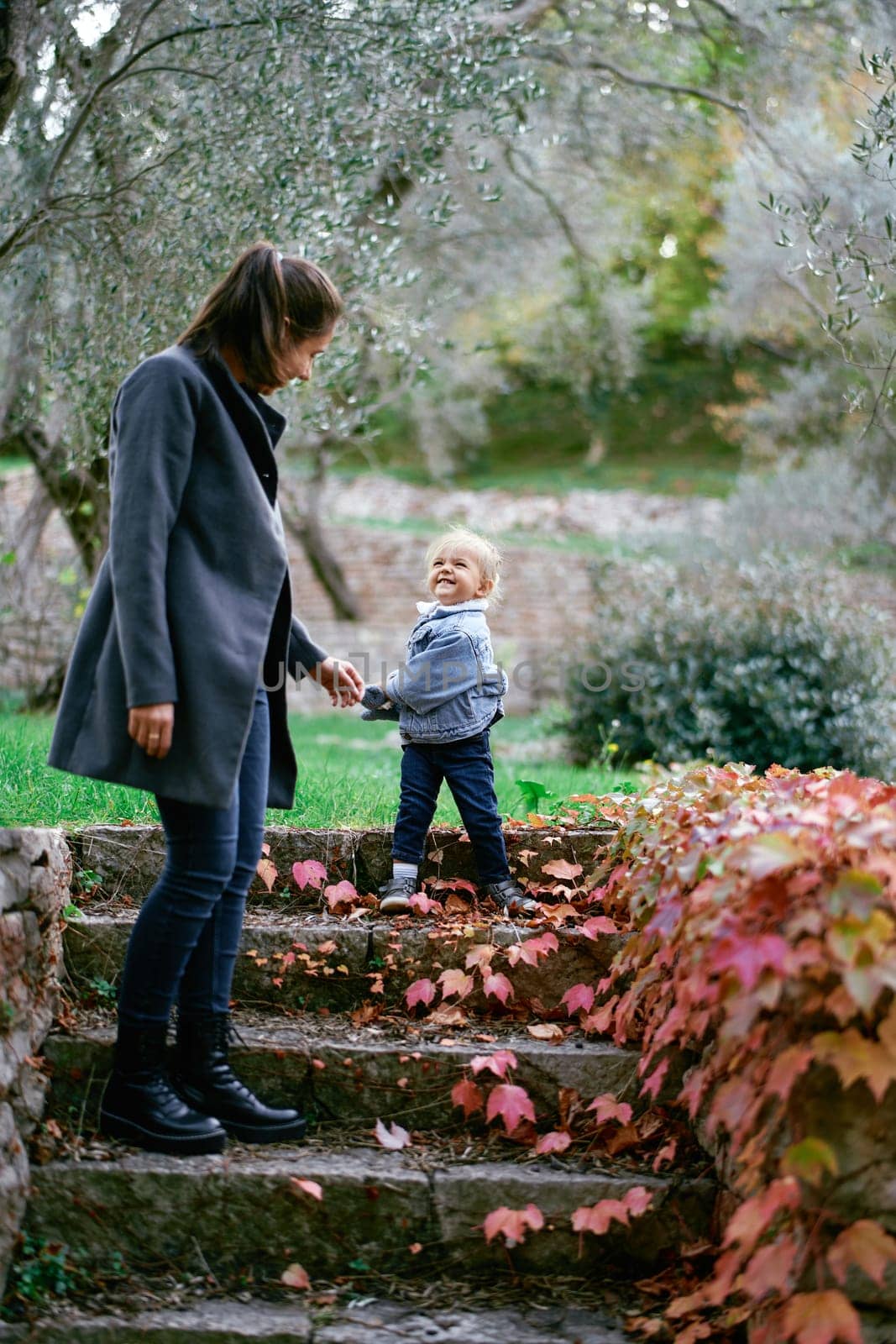 Smiling little girl stands with her mother on the steps of the park by Nadtochiy