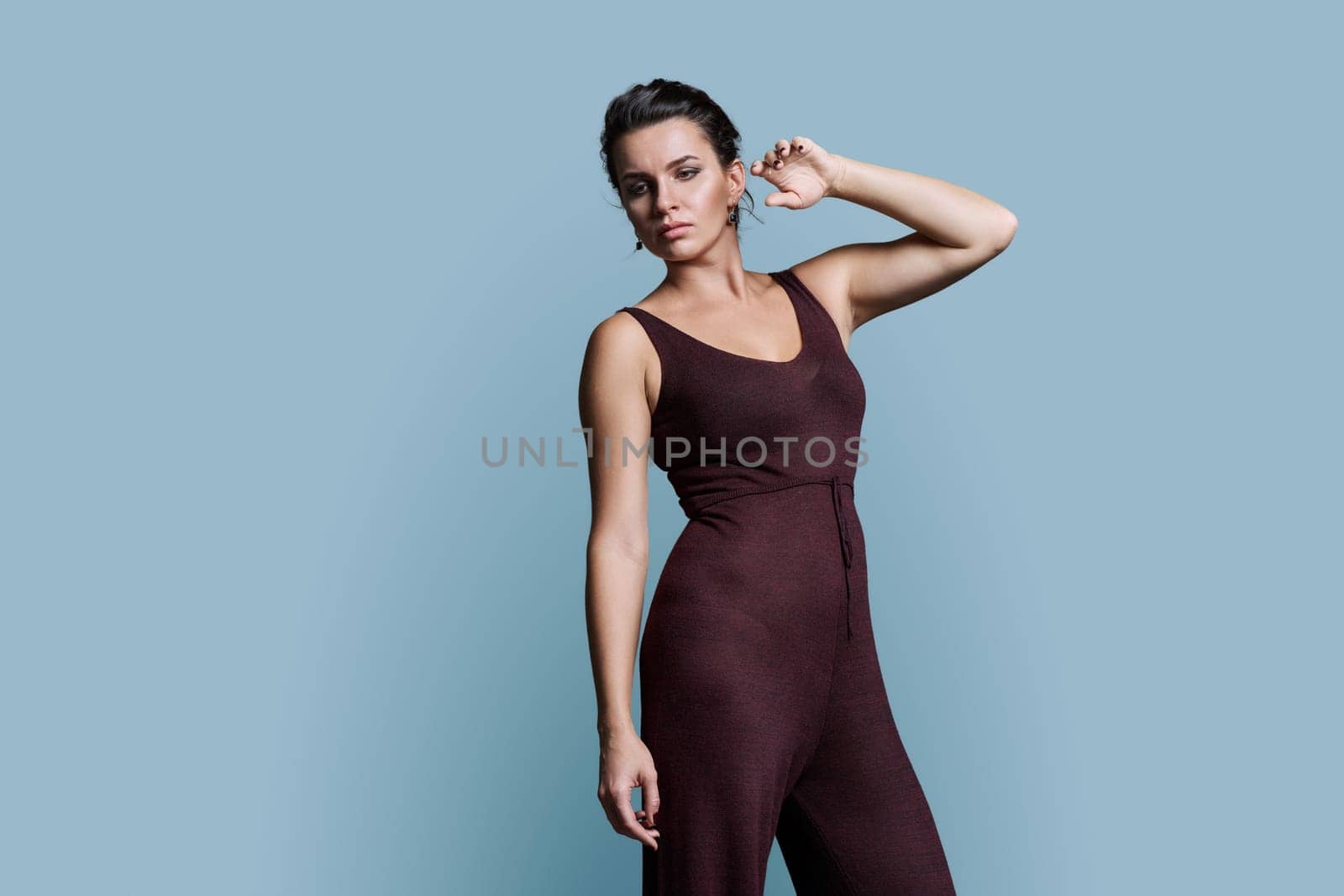 Sad pensive fashionable young woman looking down to the side, copy space gray studio background
