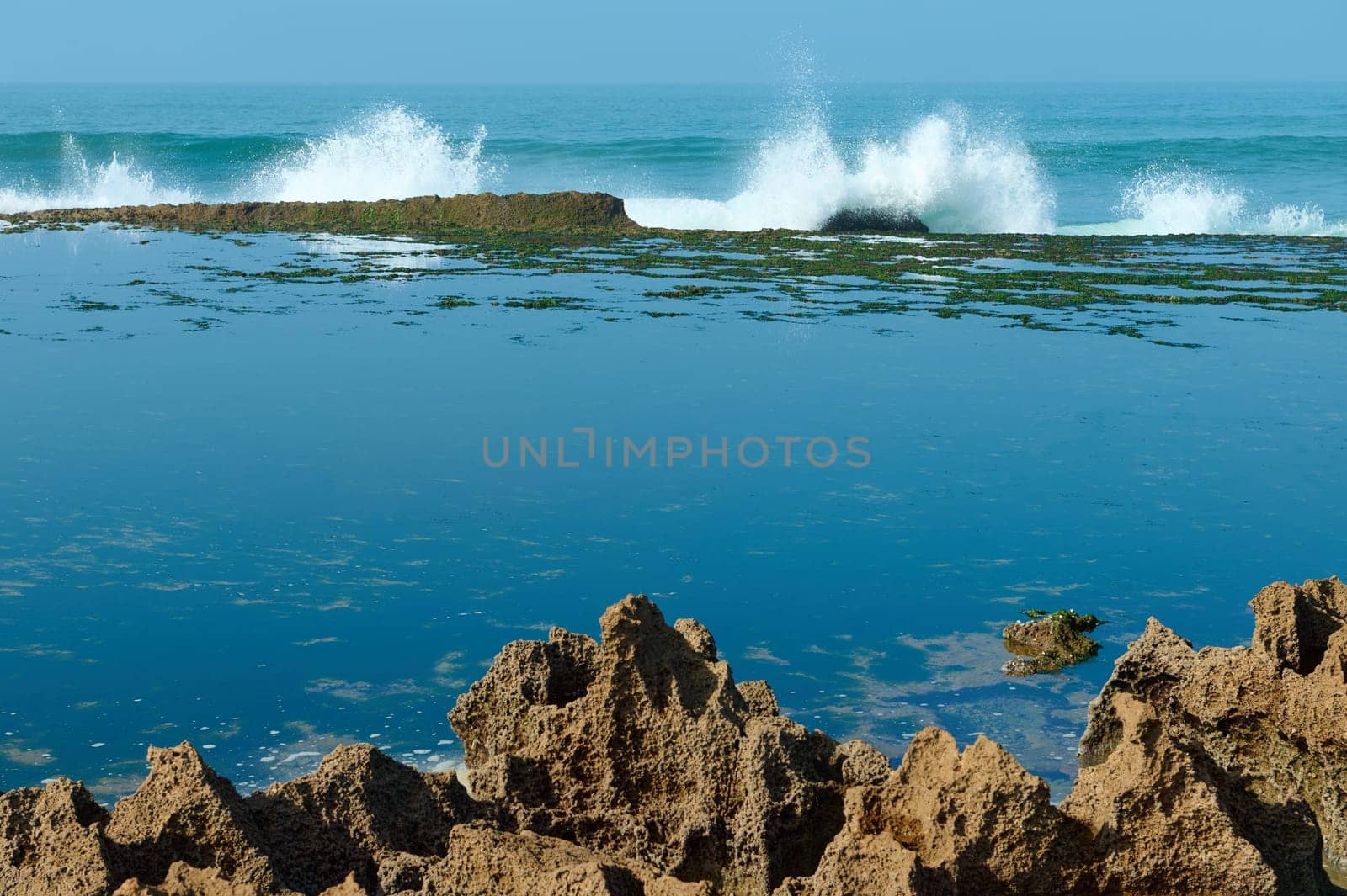 Beautiful waves splashing while crashing on the cliff. A mirror bay formed between rocks on the Atlantic ocean by artgf