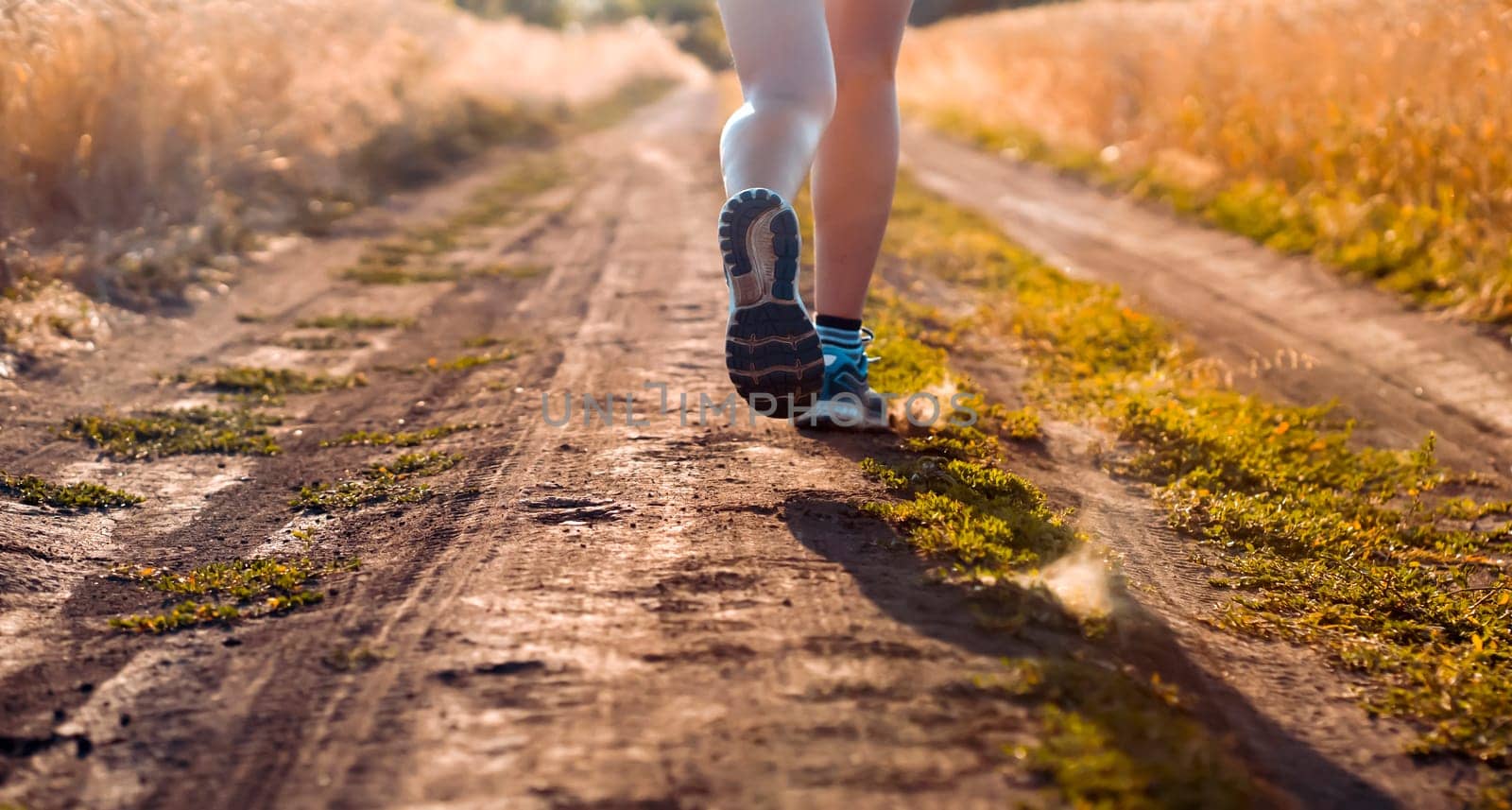 Young sports girl in a top and shorts trains outdoors, runs at sunset in the evening. A woman is engaged in trail running outdoor, preparing for a long race.