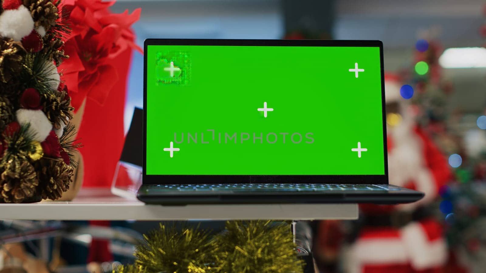 Chroma key laptop on Christmas decorated clothing store display table showing information about products. Green screen device in festive adorn fashion boutique useful for looking up clothes prices
