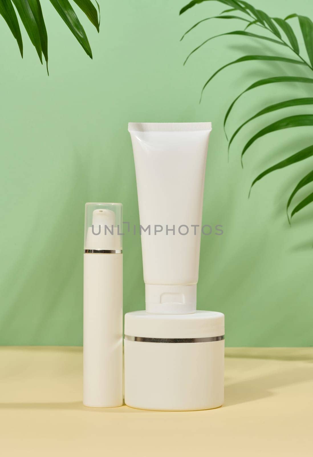 White plastic tubes, jars on a green background, containers for cosmetic creams and gels, by ndanko
