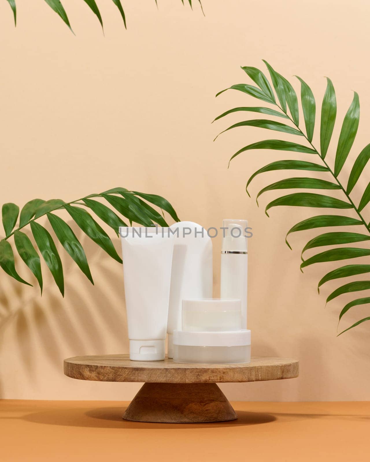 White plastic tubes, jars on a beige background, containers for cosmetic creams and gels by ndanko