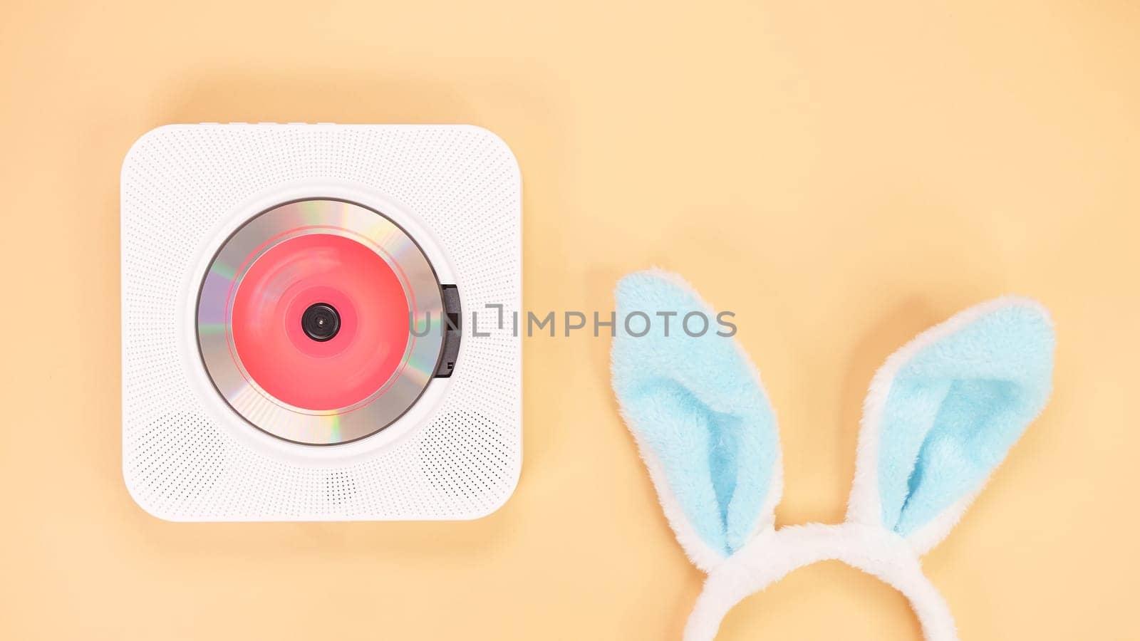 White cd player with red disc with bunny ears on yellow background. Love music, Easter bunny, retro Love song, space for text. by JuliaDorian