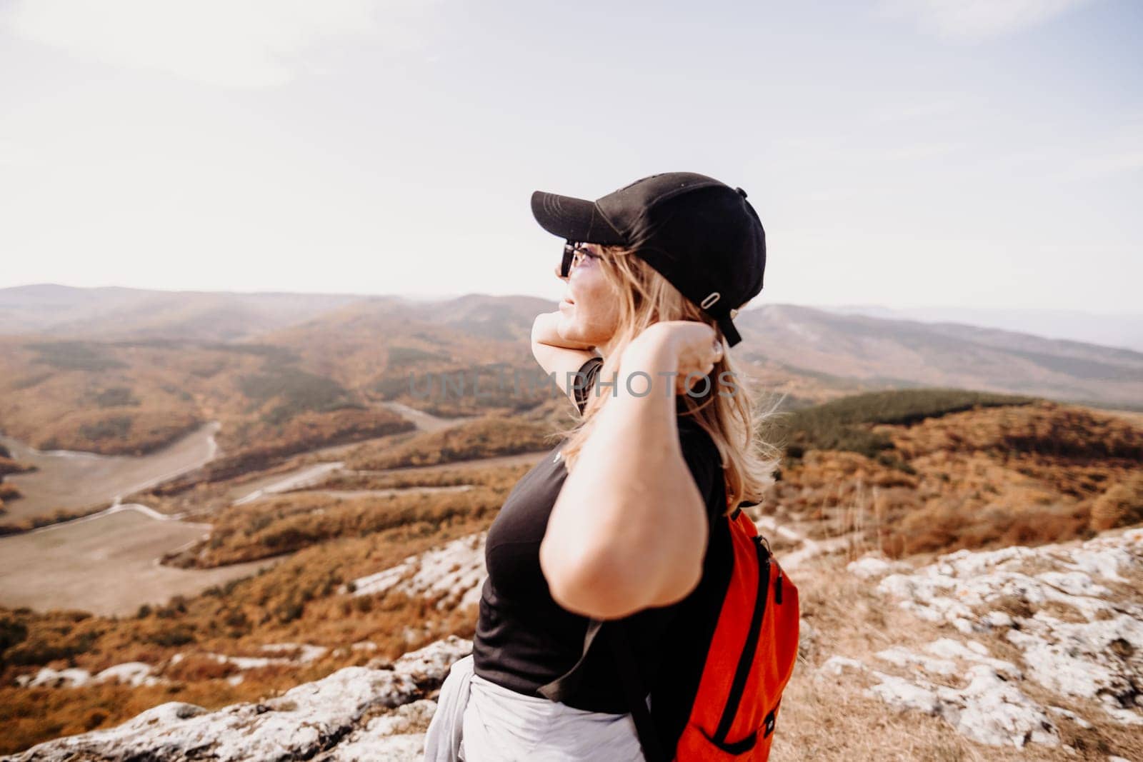 woman on mountain peak looking in beautiful mountain valley in autumn. Landscape with sporty young woman, blu sky in fall. Hiking. Nature.