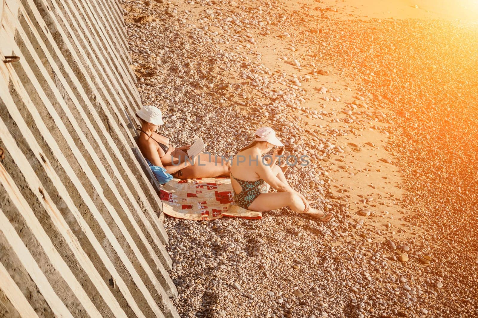 Beautiful Young Woman reading book and Sitting on the Beach Chair Under Beach Umbrella on Vacation. Summer Holidays Travel Concept.