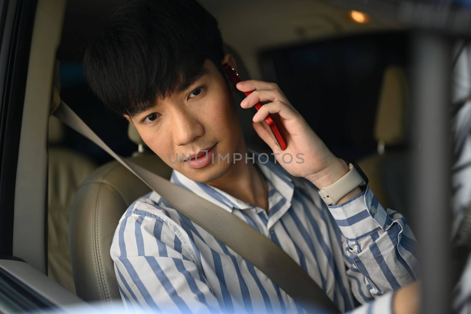 Young businessman talking with his cellphone while driving a car in the city. by prathanchorruangsak